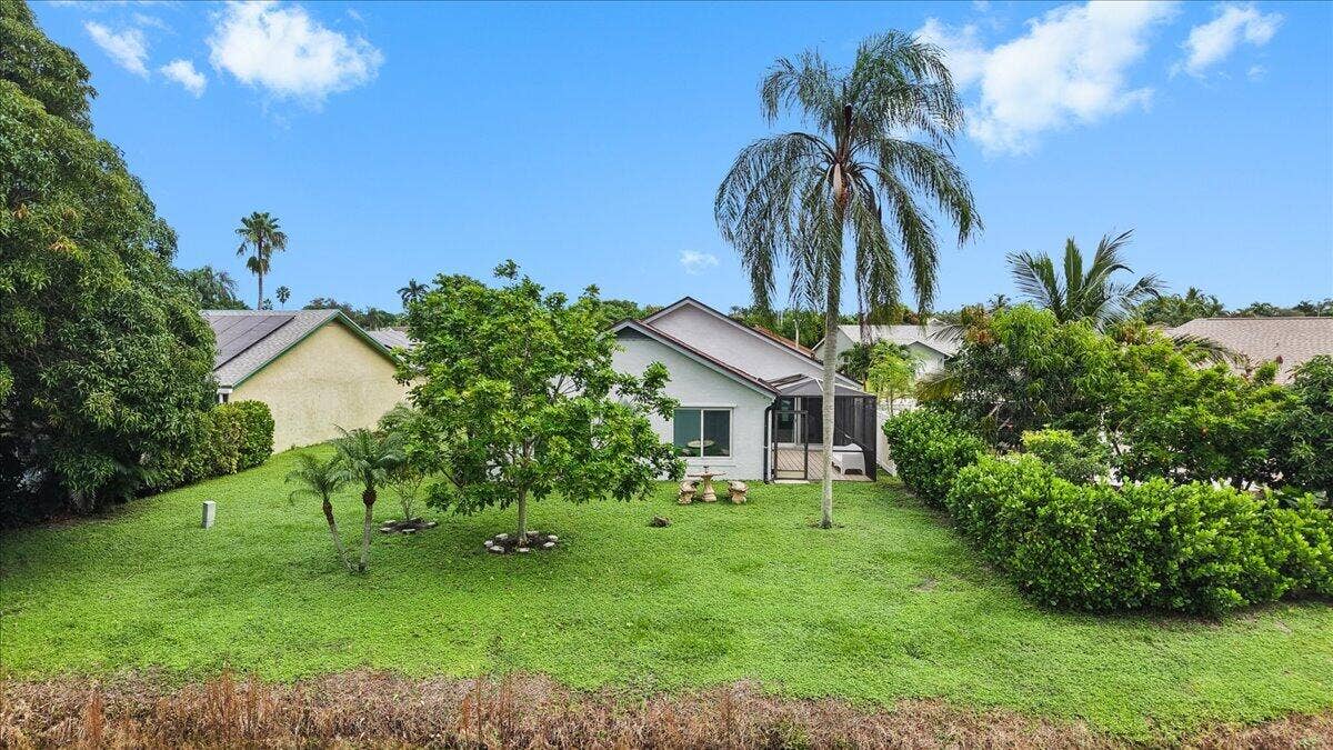 Expansive backyard featuring a sprawling lawn, mature trees, dense privacy hedges, and a screened rear porch