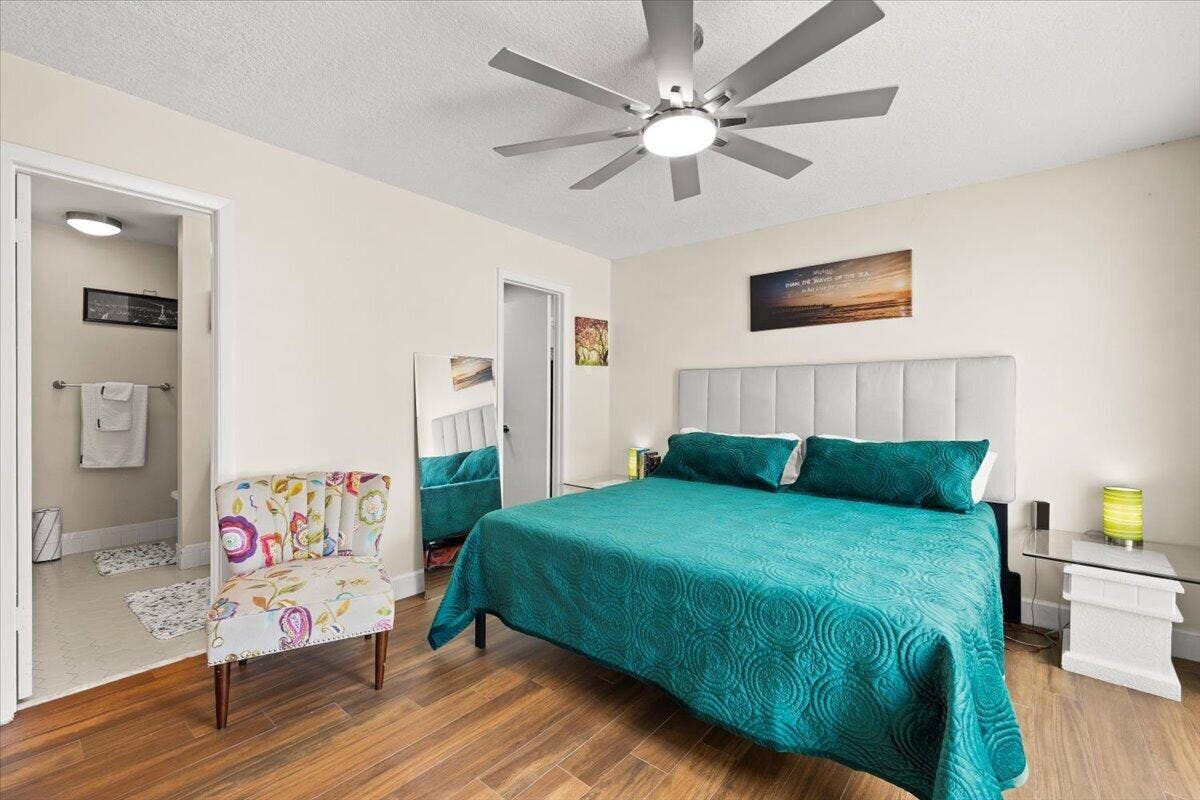 Room interior featuring wood-finish flooring, a multi-blade ceiling fan with integrated lighting, and a neutral wall palette
