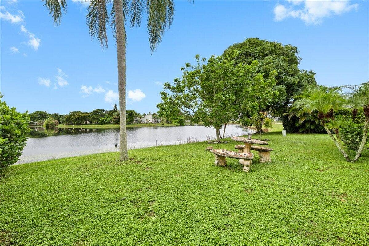 Waterfront lot featuring mature trees, a natural grass lawn, and a stone-finish picnic table