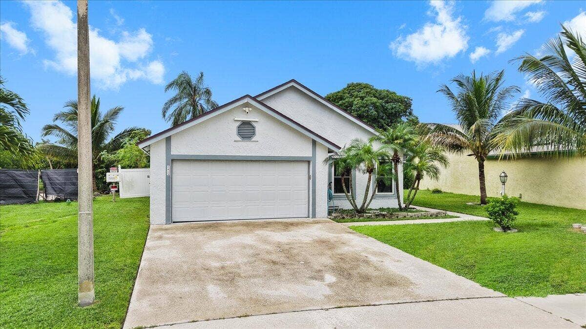 Single-story residence featuring a stucco exterior, concrete driveway, attached two-car garage, and established landscaping