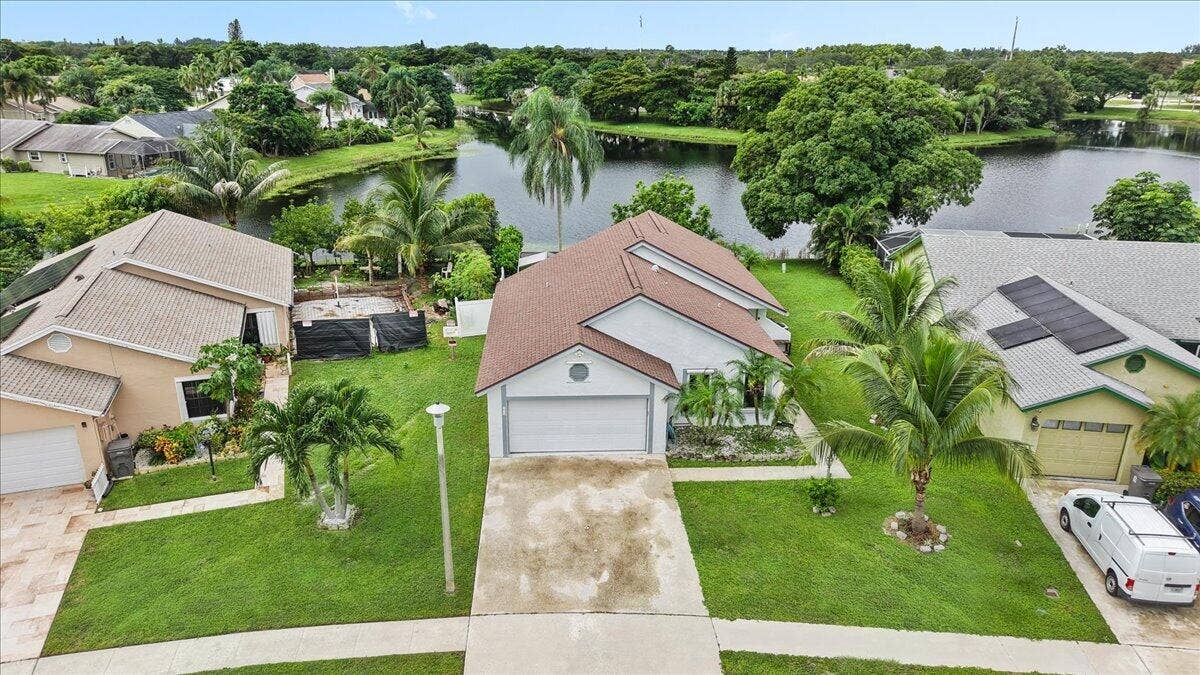 Single-story residence featuring a gabled roof, attached two-car garage, concrete driveway, and backyard waterfront access