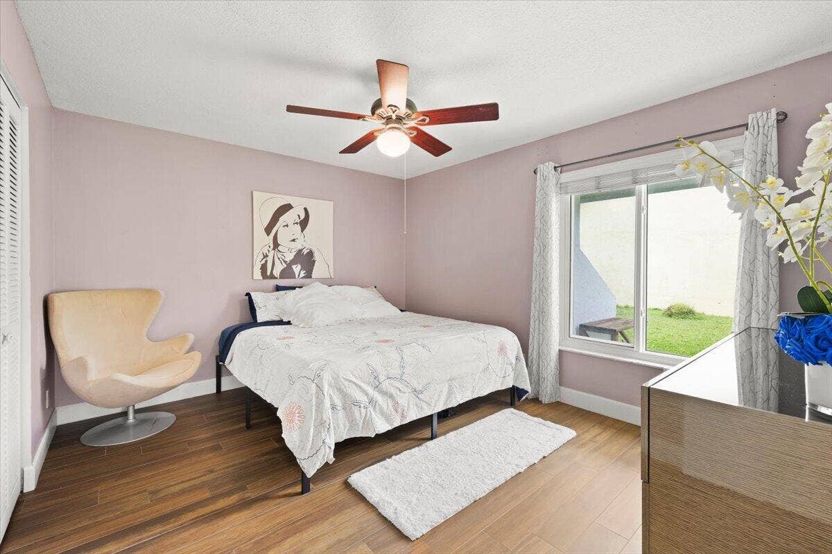 Wood-finish flooring, multi-pane window, and central ceiling fan with integrated lighting