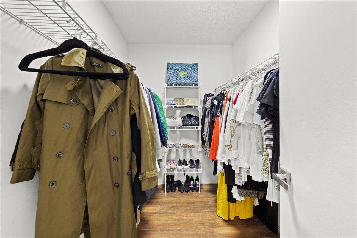 Walk-in storage space featuring wood-finish flooring and integrated wire shelving systems