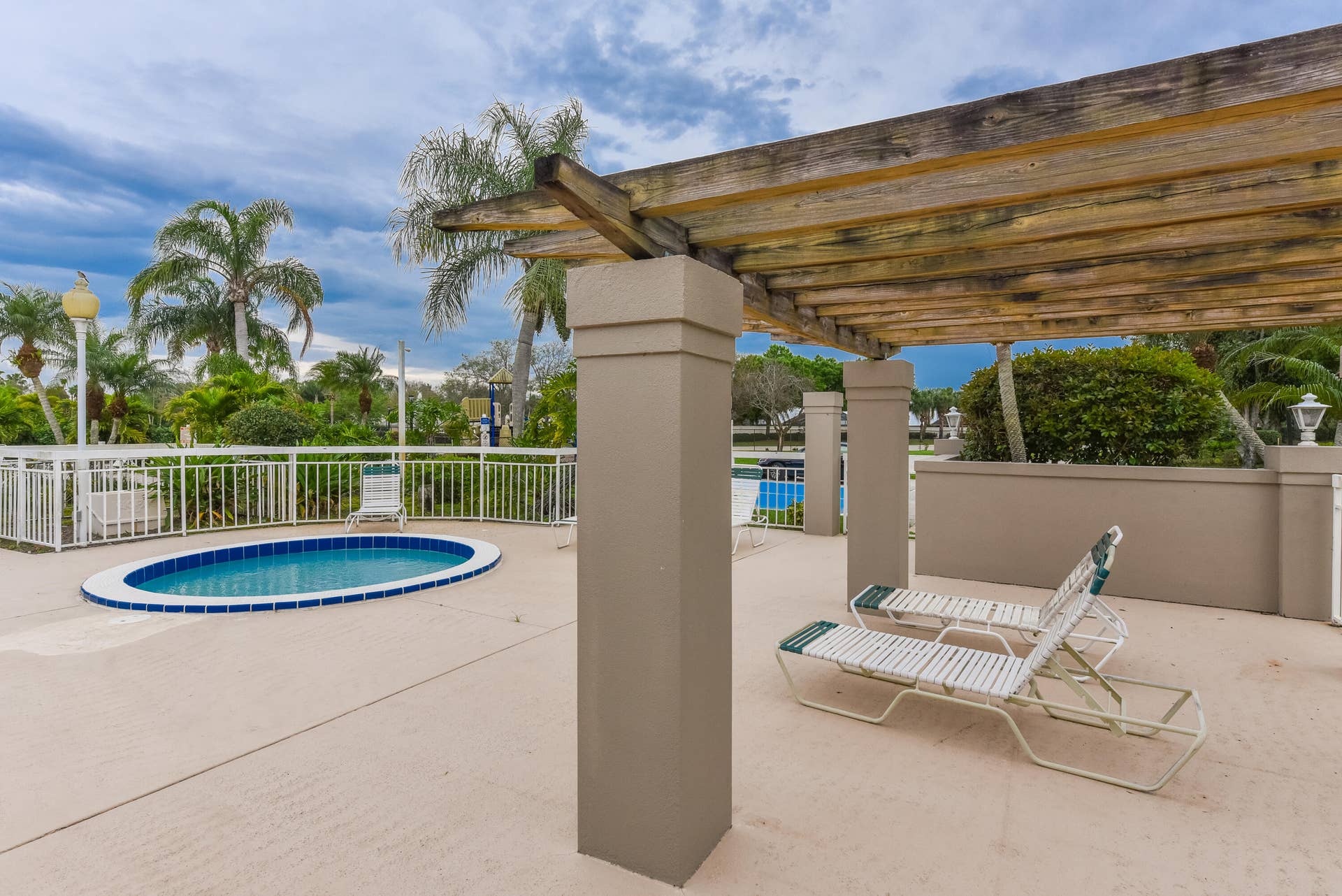 3233 SW SUNSET TRACE Circle, Palm City, FL 34990 Outdoor terrace featuring a wood-beam pergola, concrete decking, built-in pool, and white metal fencing