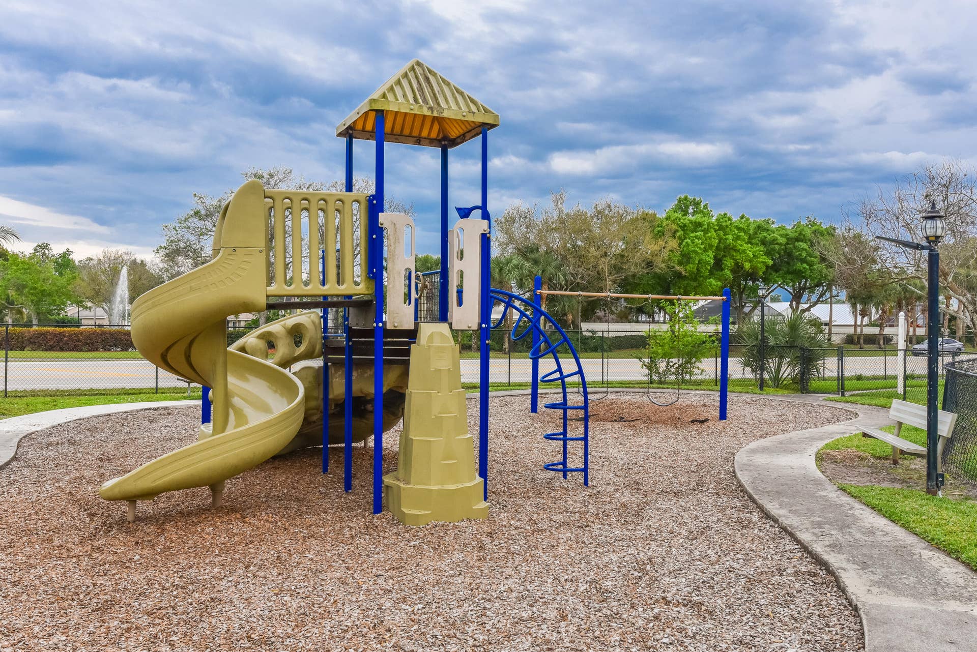3233 SW SUNSET TRACE Circle, Palm City, FL 34990 Outdoor recreation area featuring a multi-level climbing structure with a spiral slide, swing set, wood chip ground cover, and concrete perimeter walkway
