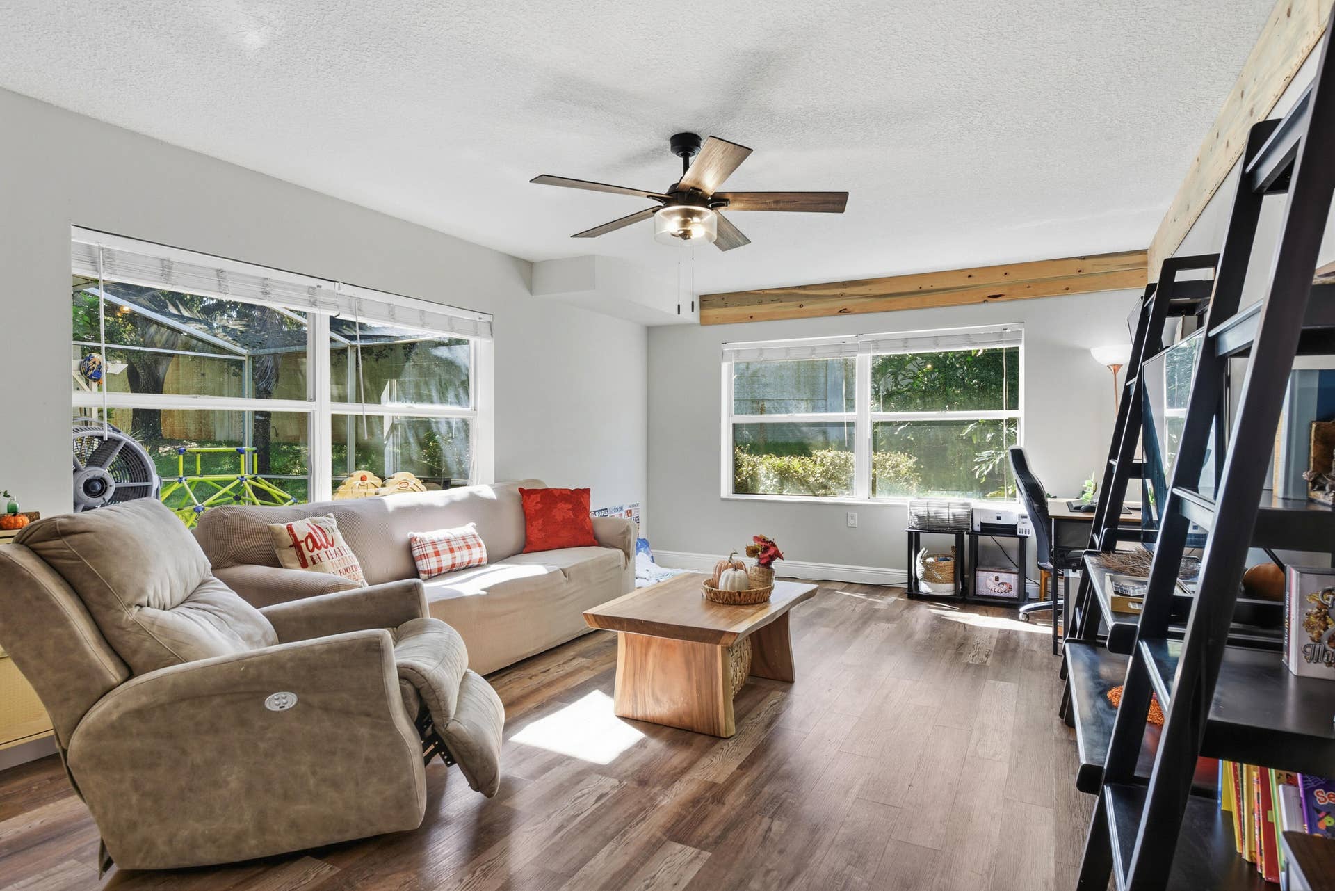 3233 SW SUNSET TRACE Circle, Palm City, FL 34990 Living area featuring wood-finish flooring, exposed natural wood ceiling beams, a ceiling fan with integrated lighting, and multiple windows