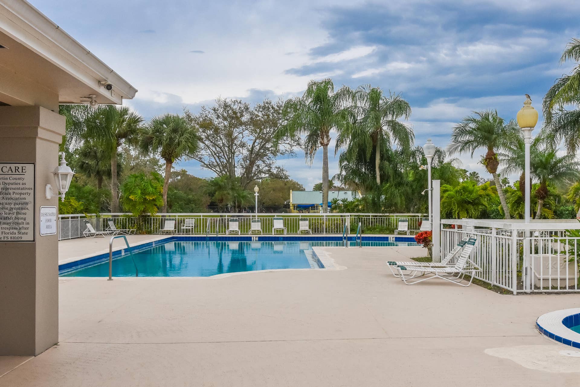 3233 SW SUNSET TRACE Circle, Palm City, FL 34990 Swimming pool with surrounding concrete deck, perimeter fencing, and exterior pole lighting