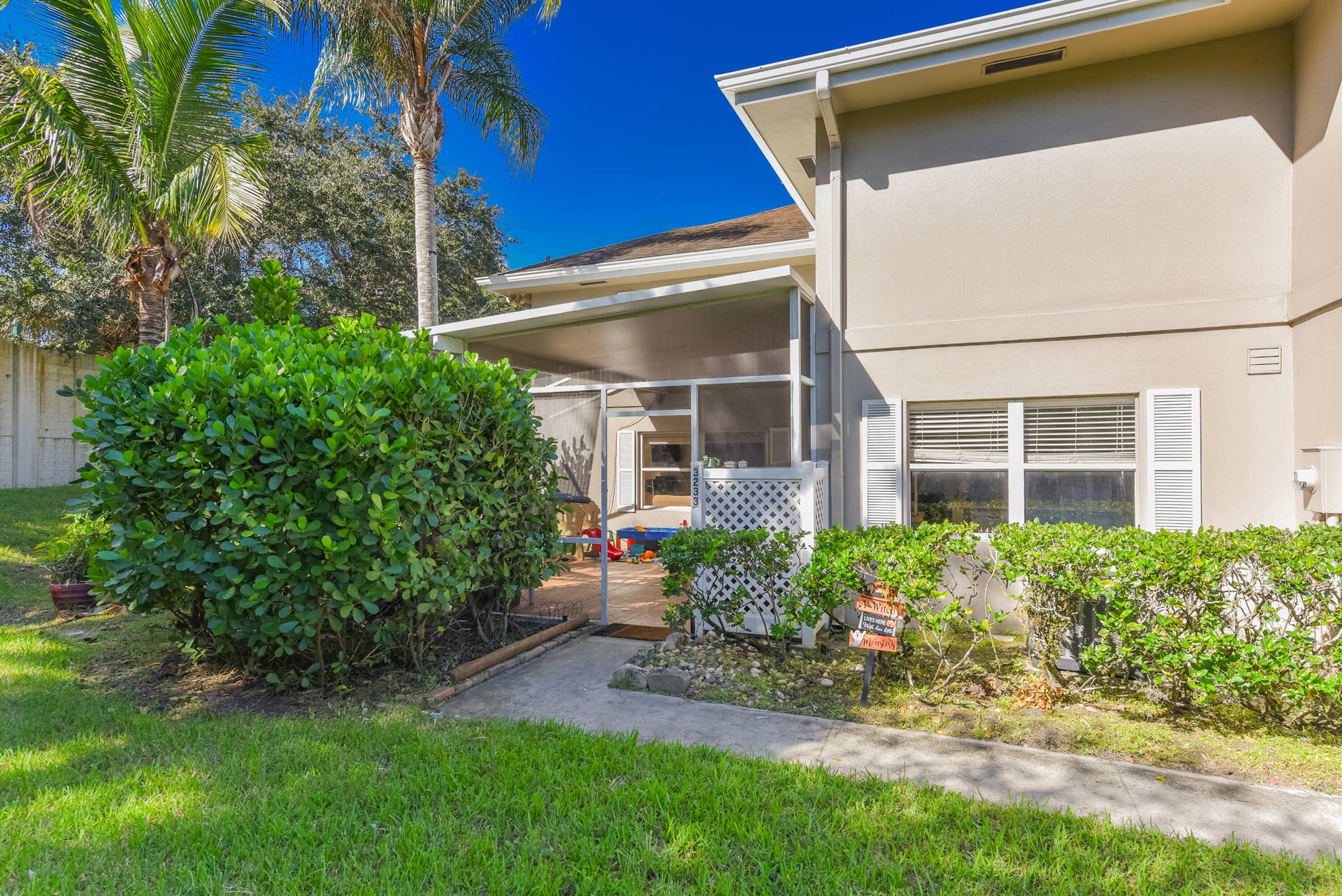 3233 SW SUNSET TRACE Circle, Palm City, FL 34990 Exterior featuring a screened-in lanai, concrete walkway, and manicured landscaping including mature palm trees