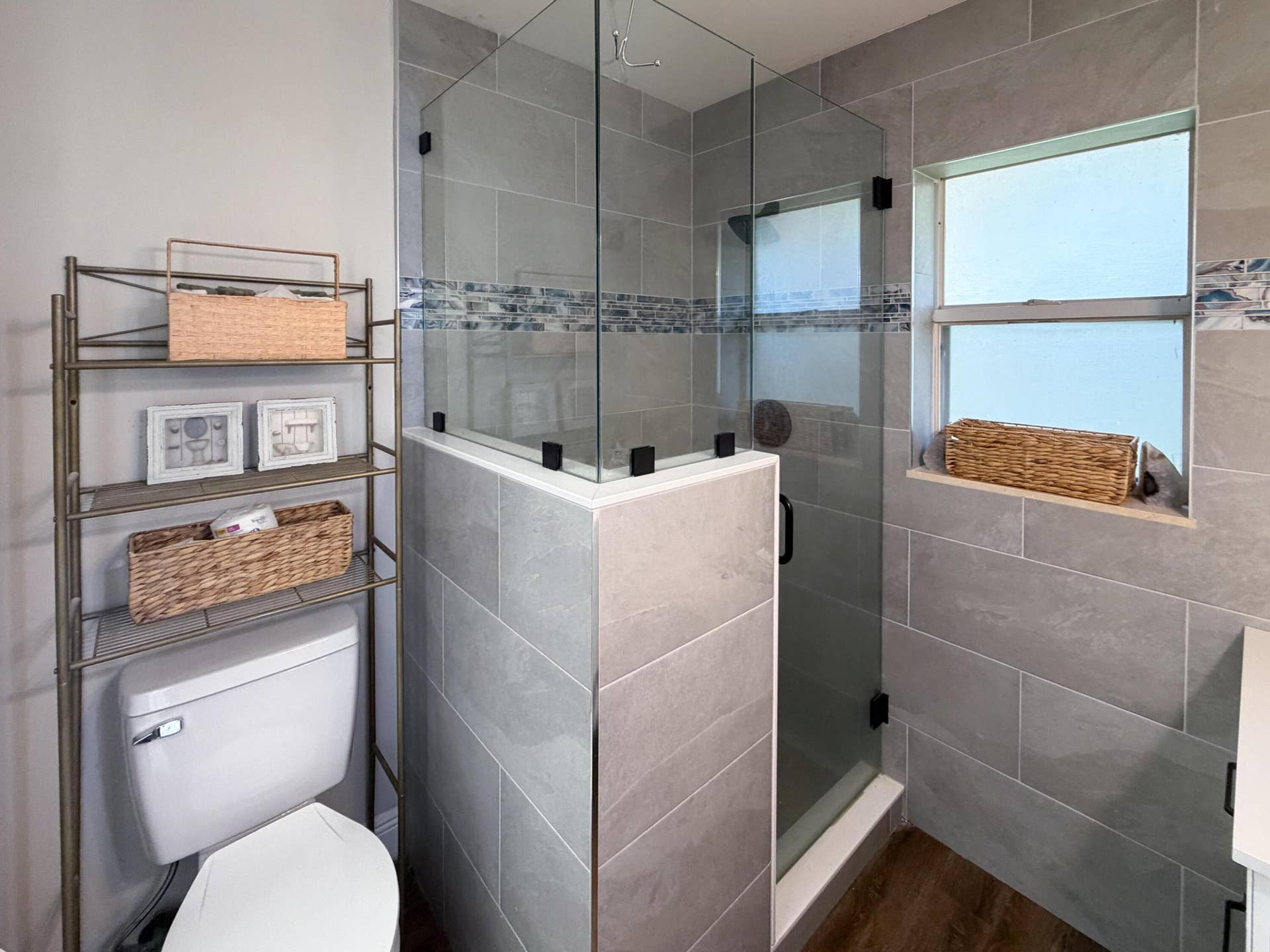 3233 SW SUNSET TRACE Circle, Palm City, FL 34990 Walk-in shower featuring glass enclosure, gray tile surround with decorative mosaic accent strip, and wood-finish flooring