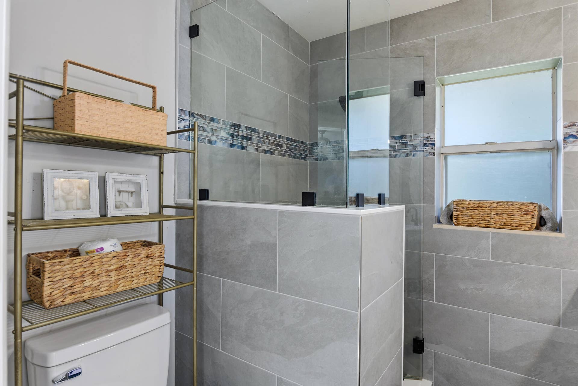 3233 SW SUNSET TRACE Circle, Palm City, FL 34990 Walk-in shower featuring large-format grey tile, a glass enclosure, decorative mosaic tile accents, and a window