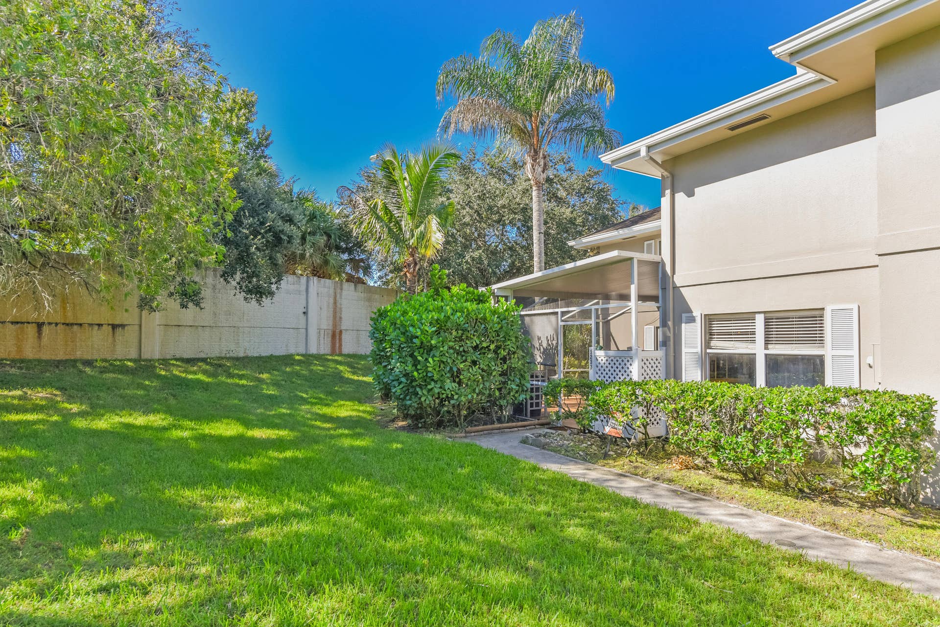 3233 SW SUNSET TRACE Circle, Palm City, FL 34990 Backyard featuring a manicured lawn, concrete walkway, screened-in porch, and perimeter wall