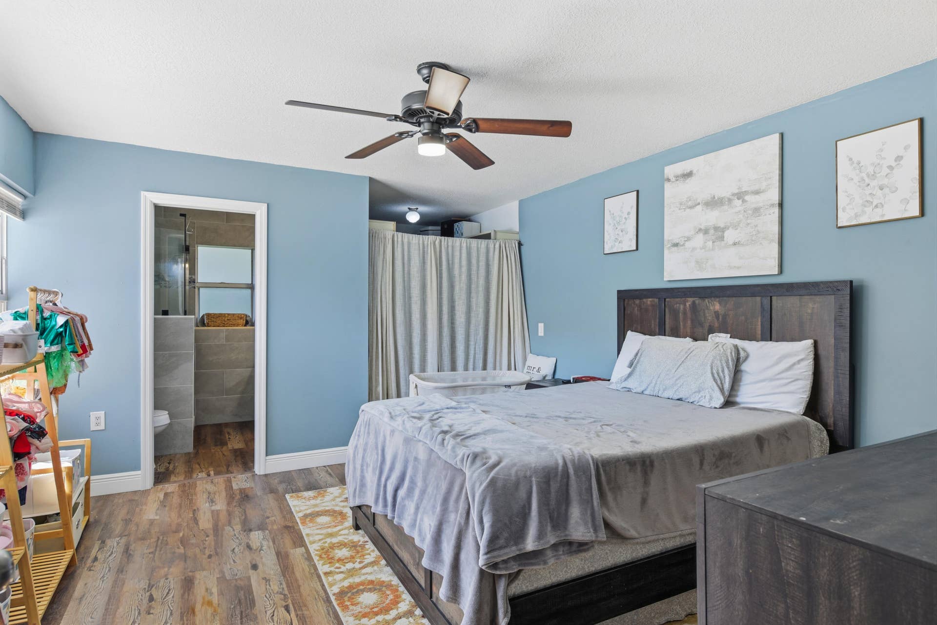 3233 SW SUNSET TRACE Circle, Palm City, FL 34990 Bedroom featuring wood-finish flooring, a multi-blade ceiling fan with integrated lighting, and a doorway entry to a tiled bathroom