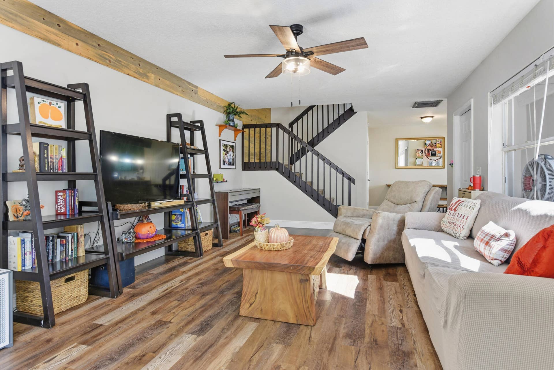 3233 SW SUNSET TRACE Circle, Palm City, FL 34990 Living area featuring wood-finish flooring, exposed timber ceiling beam, and a staircase with a dark-finish wood railing