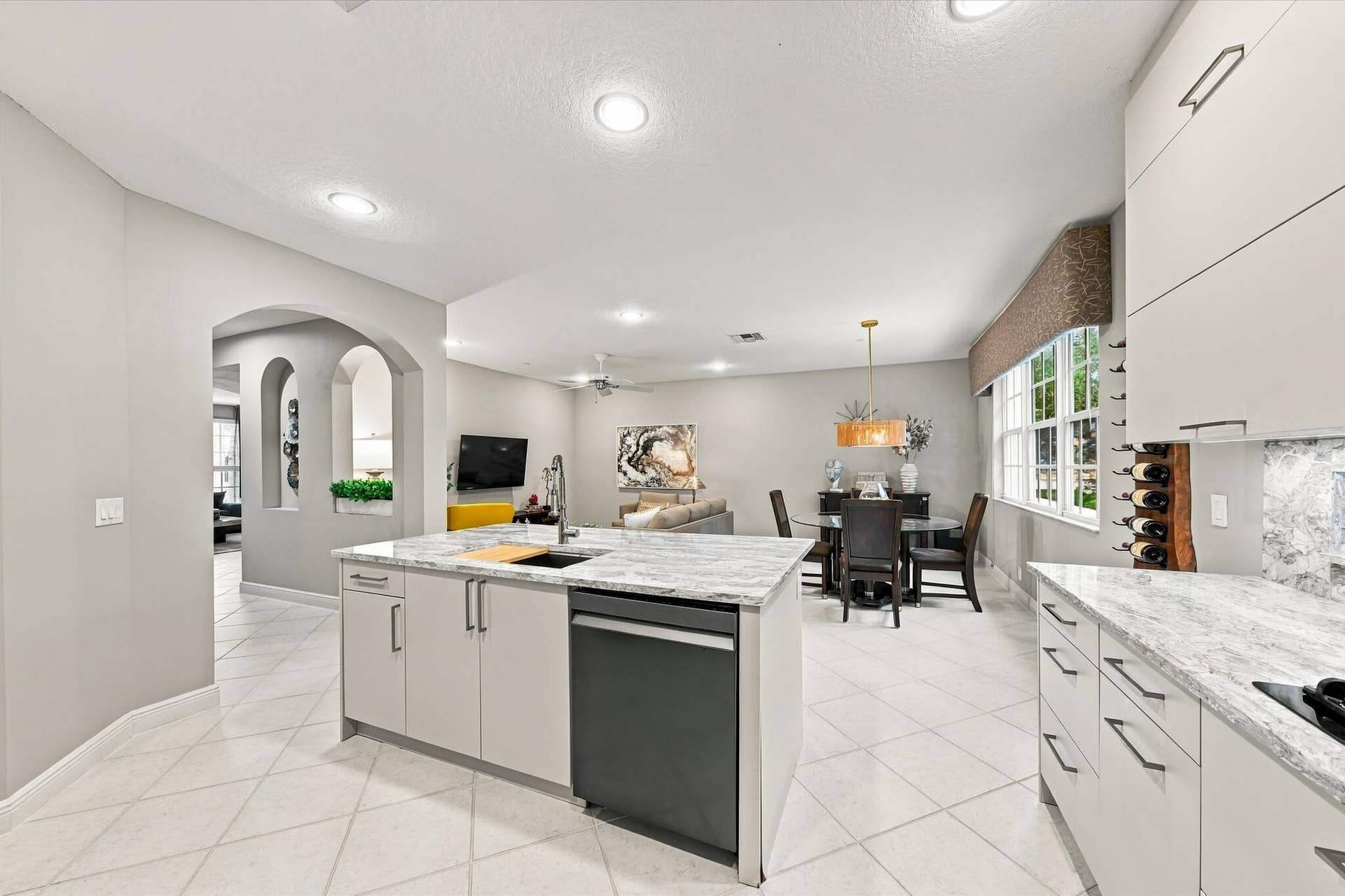 5545 NE Trieste Way, Boca Raton, FL 33487 Kitchen featuring light-toned cabinetry, stone-finish countertops, recessed lighting, tile flooring, and a central island with a built-in dishwasher
