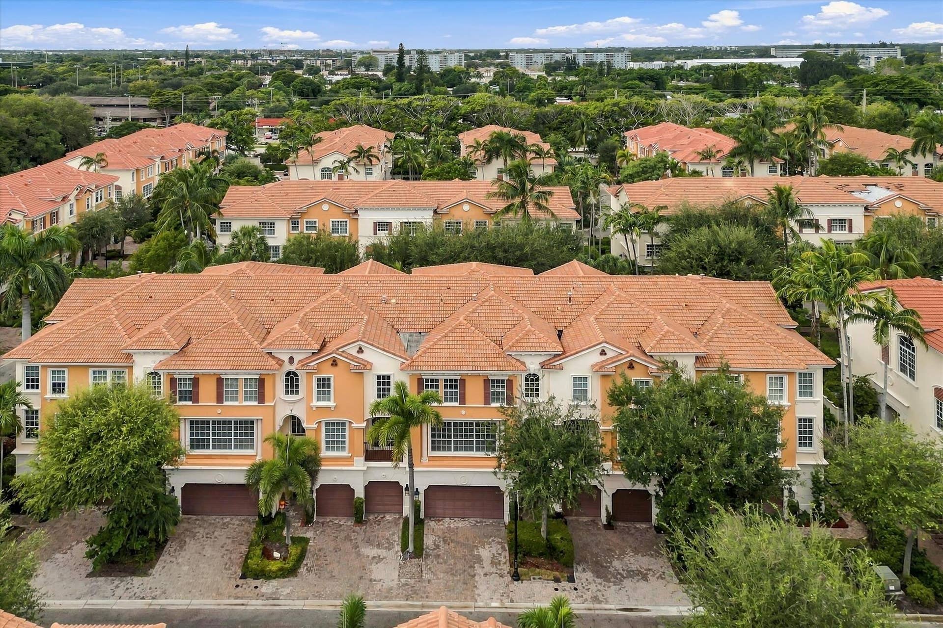 5545 NE Trieste Way, Boca Raton, FL 33487 Multi-story residential complex featuring terracotta-style roofing, stucco exterior finish, multiple attached garages, and paver driveways