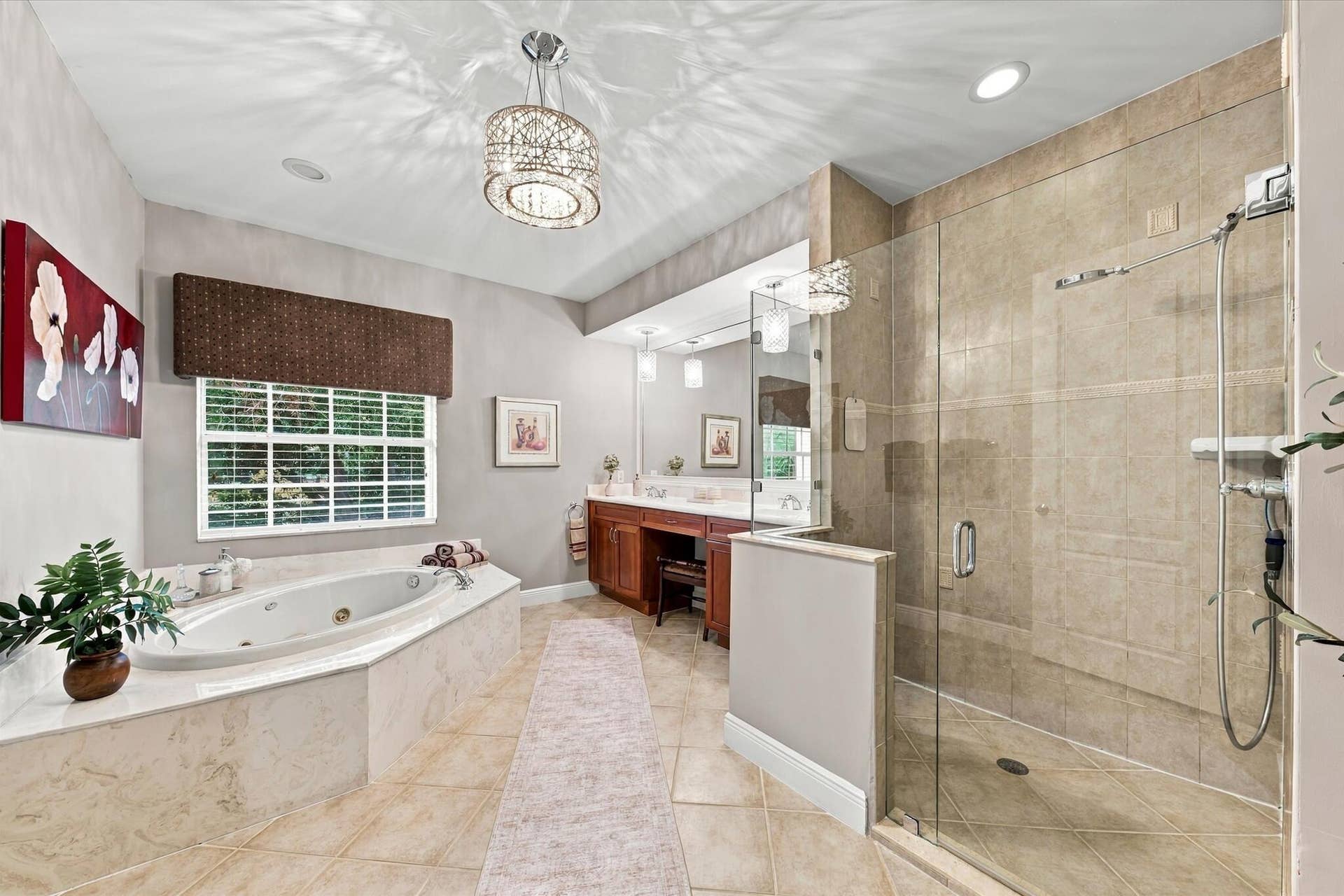 5545 NE Trieste Way, Boca Raton, FL 33487 Jetted soaking tub with tile surround, walk-in glass-enclosed shower, dual-sink vanity with built-in cabinetry, crystal-accented light fixture, and tile flooring