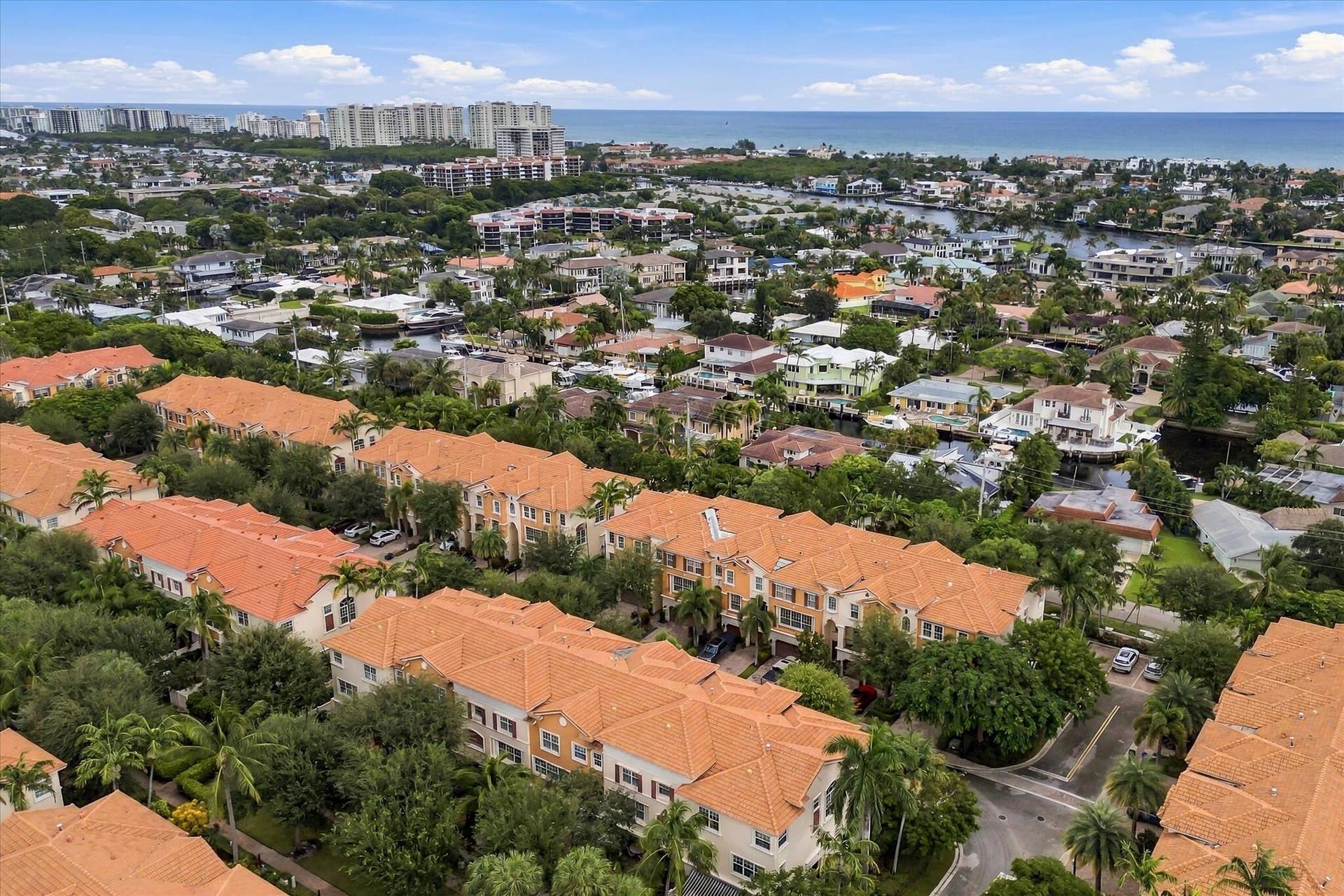 5545 NE Trieste Way, Boca Raton, FL 33487 Aerial view featuring Mediterranean-style architecture with clay tile roofs, mature palm trees, and proximity to the coastline