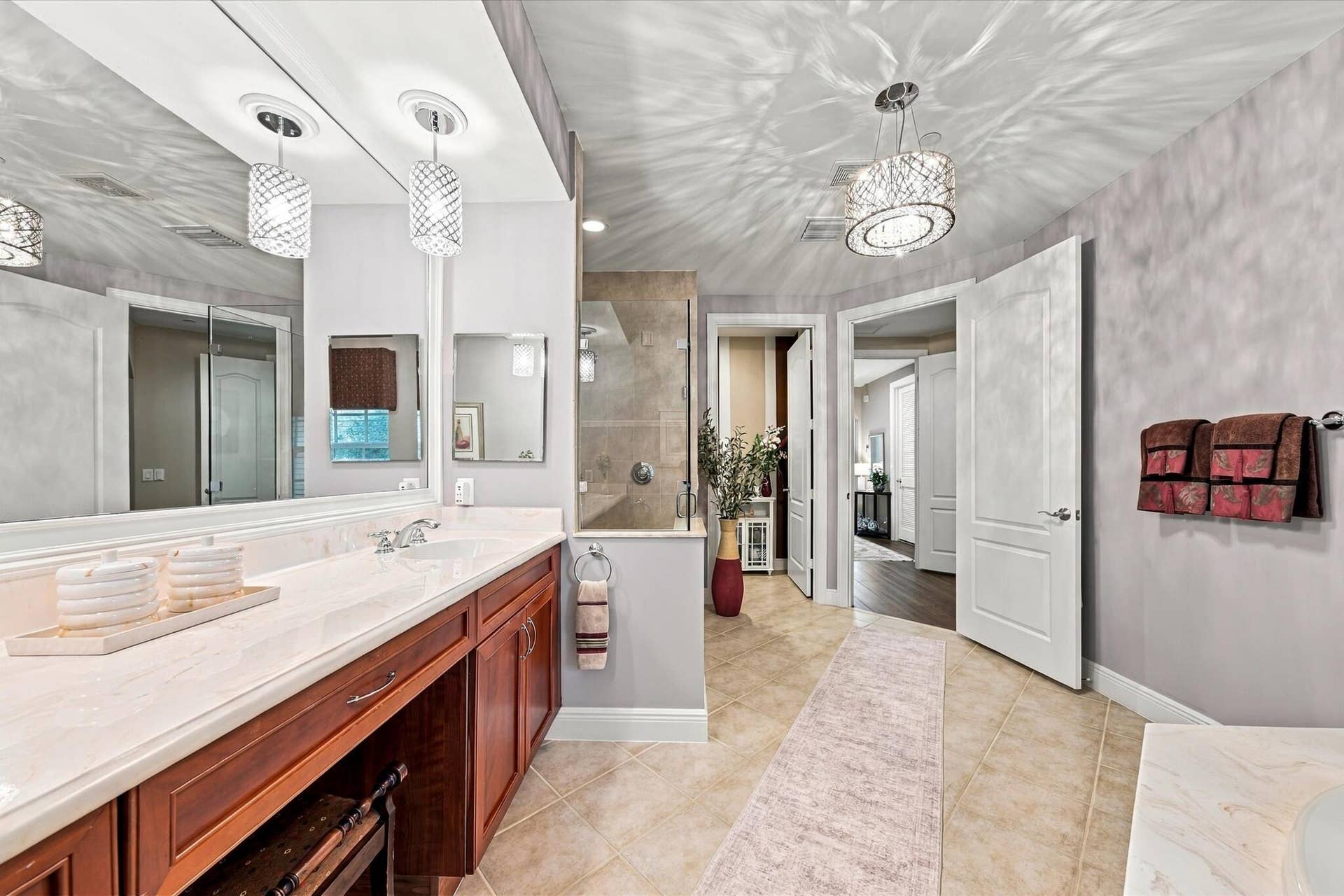 5545 NE Trieste Way, Boca Raton, FL 33487 Bathroom vanity featuring a light-toned stone countertop, dual undermount sinks, wood-finish cabinetry, and decorative glass pendant lighting