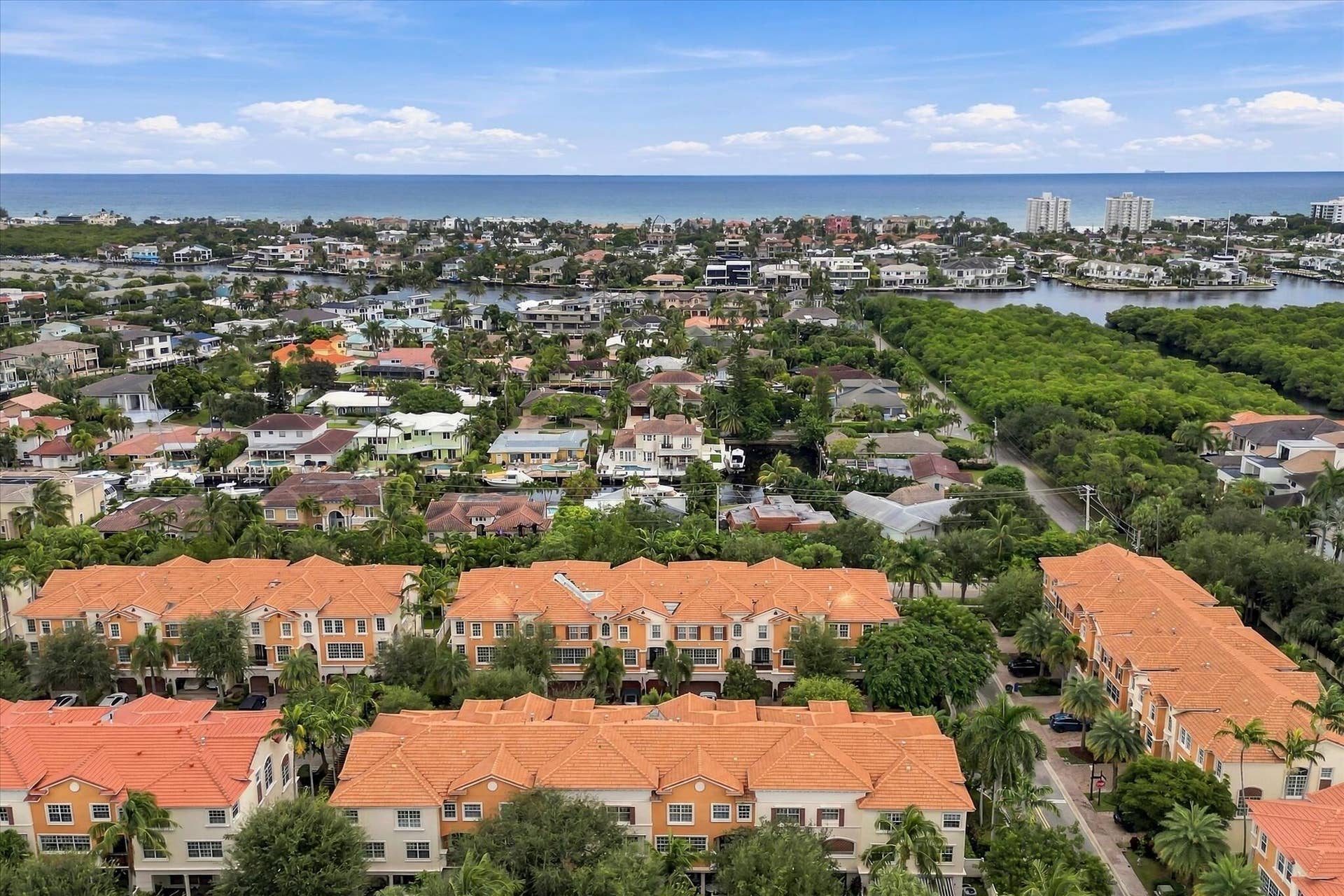 5545 NE Trieste Way, Boca Raton, FL 33487 Aerial perspective of a multi-unit complex featuring terra-cotta tile roofs, stucco exterior finish, mature palm trees, and proximity to coastal waterways
