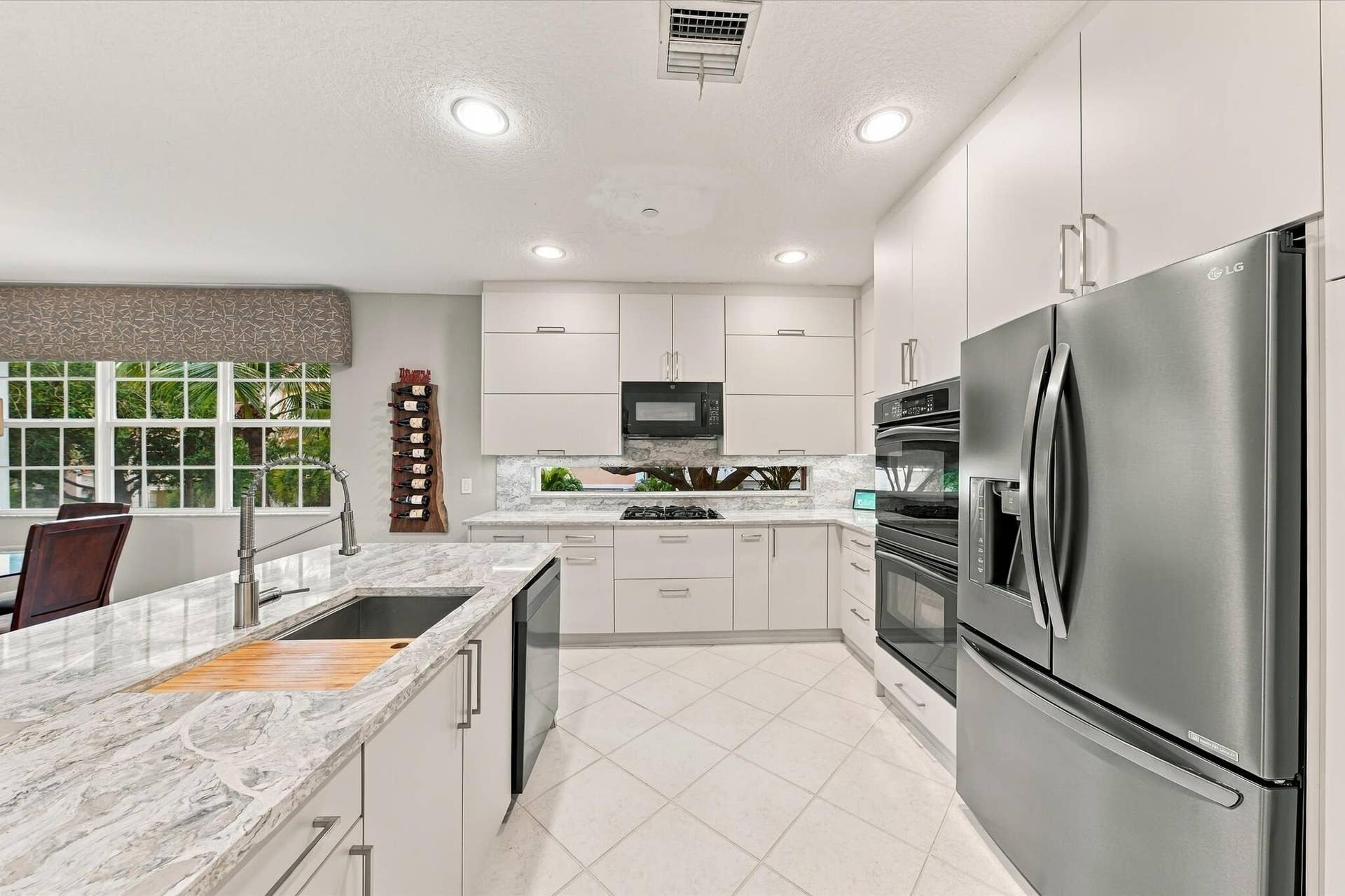 5545 NE Trieste Way, Boca Raton, FL 33487 Kitchen featuring flat-panel cabinetry, stone countertops, a stainless steel double wall oven, a stainless steel refrigerator, and recessed lighting