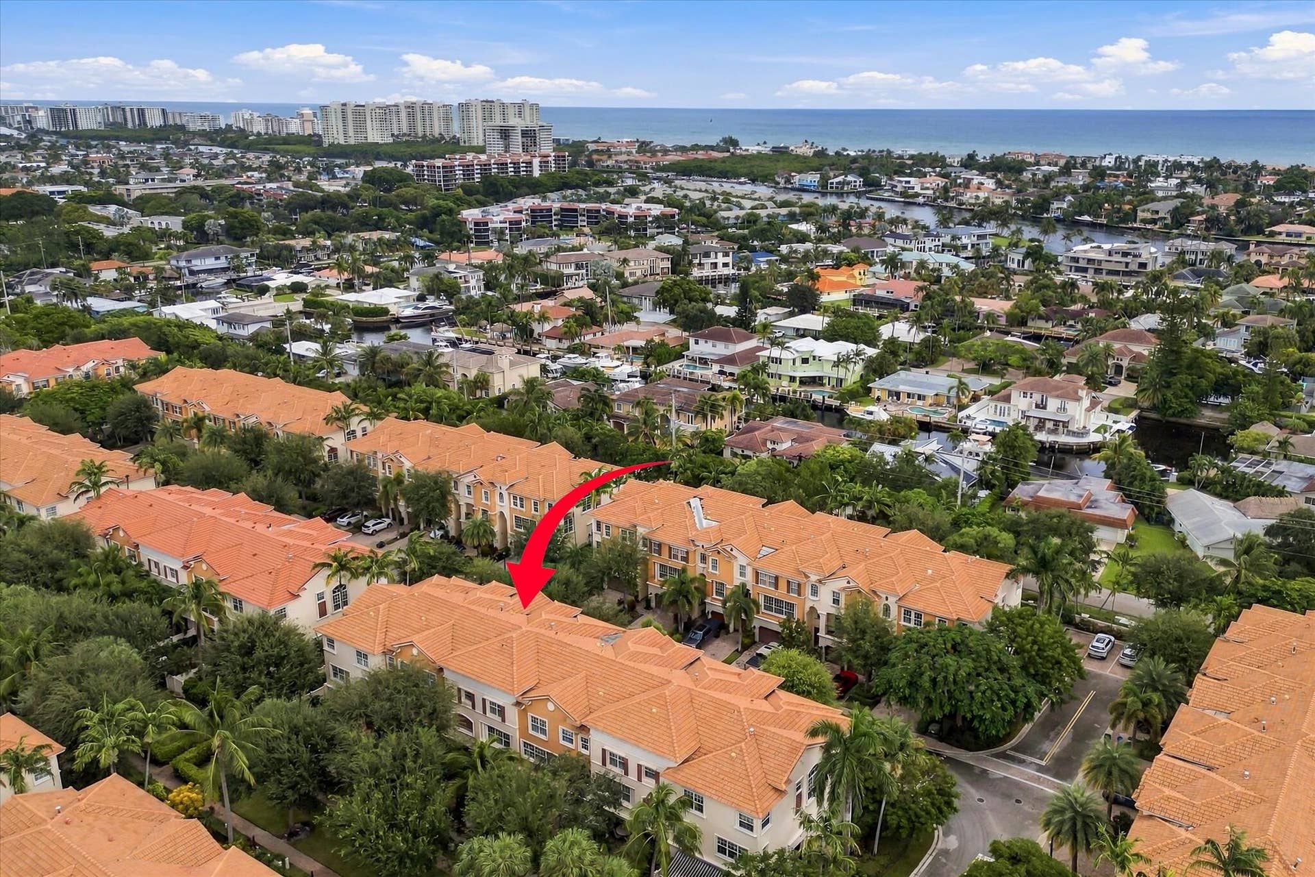 5545 NE Trieste Way, Boca Raton, FL 33487 Aerial perspective of a multi-story residential building featuring a terracotta tile roof, stucco exterior, and mature landscaping