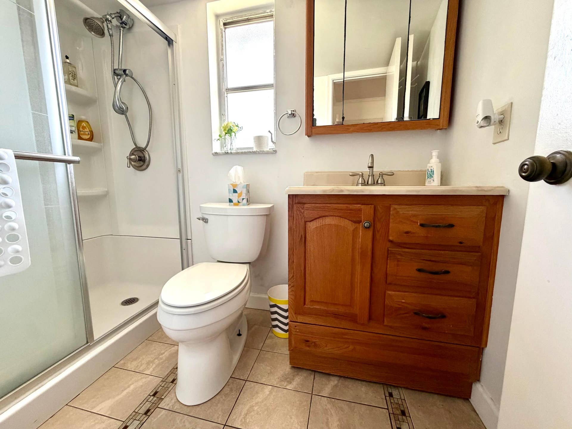 Bathroom featuring a shower with a sliding glass enclosure, a wooden vanity cabinet, a stone-surfaced countertop, and tile flooring