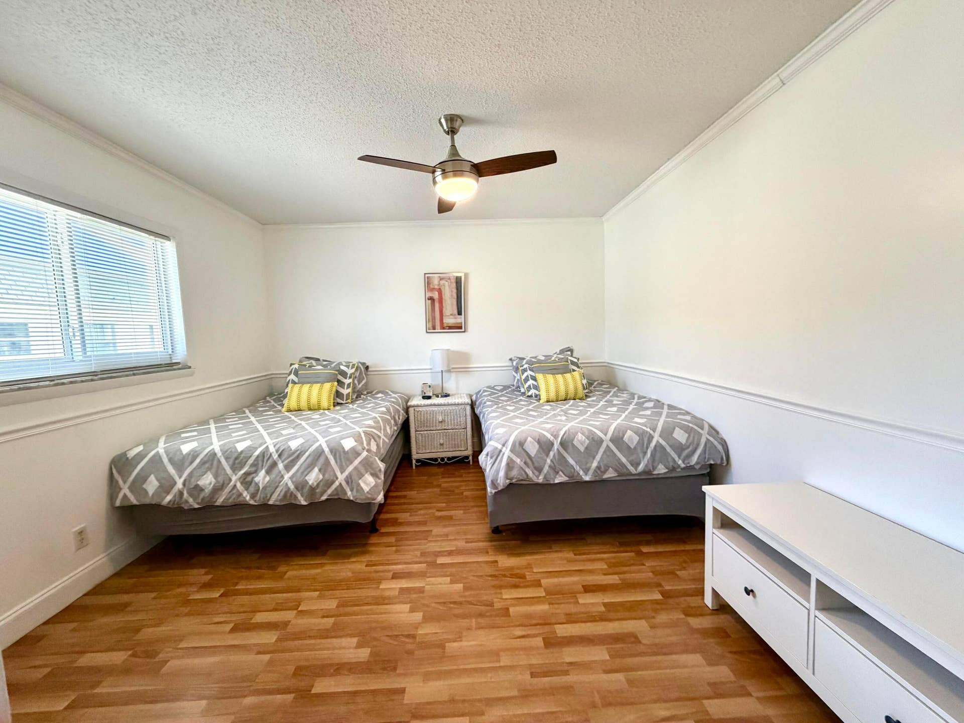 Wood-finish flooring, chair rail molding, and a brushed nickel ceiling fan with integrated lighting