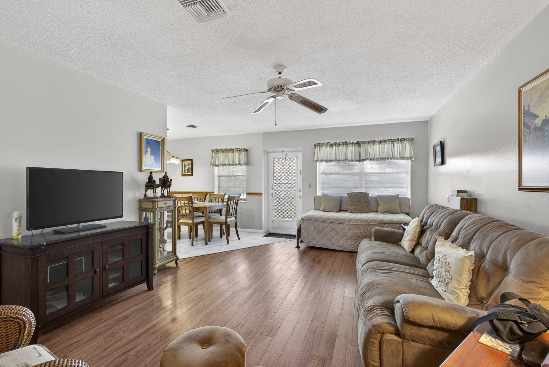 Wood-finish flooring, white-finish walls, and ceiling-mounted fan with integrated lighting