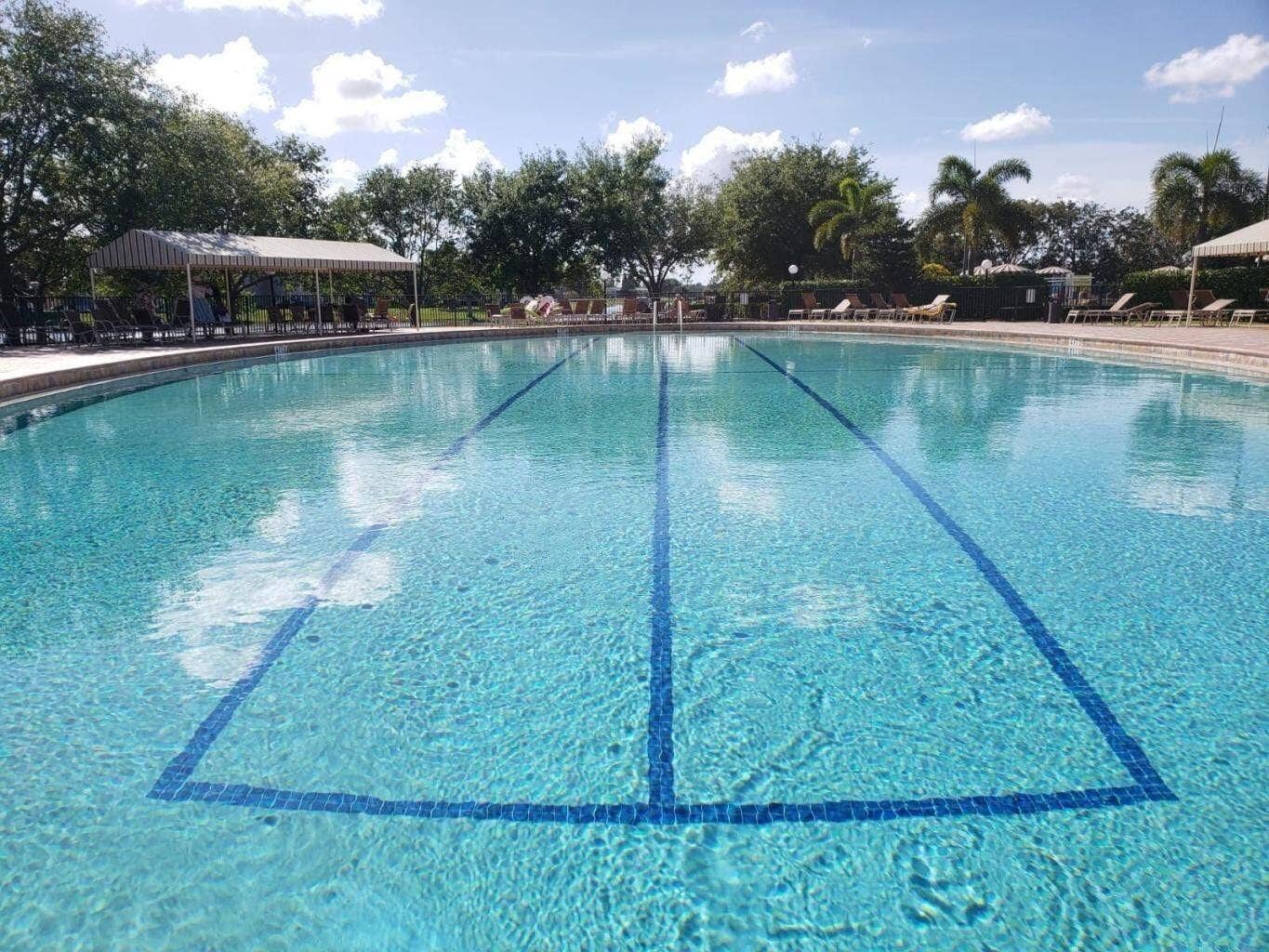 Oversized lap pool with inlaid lane markers, concrete decking, and covered shade structures