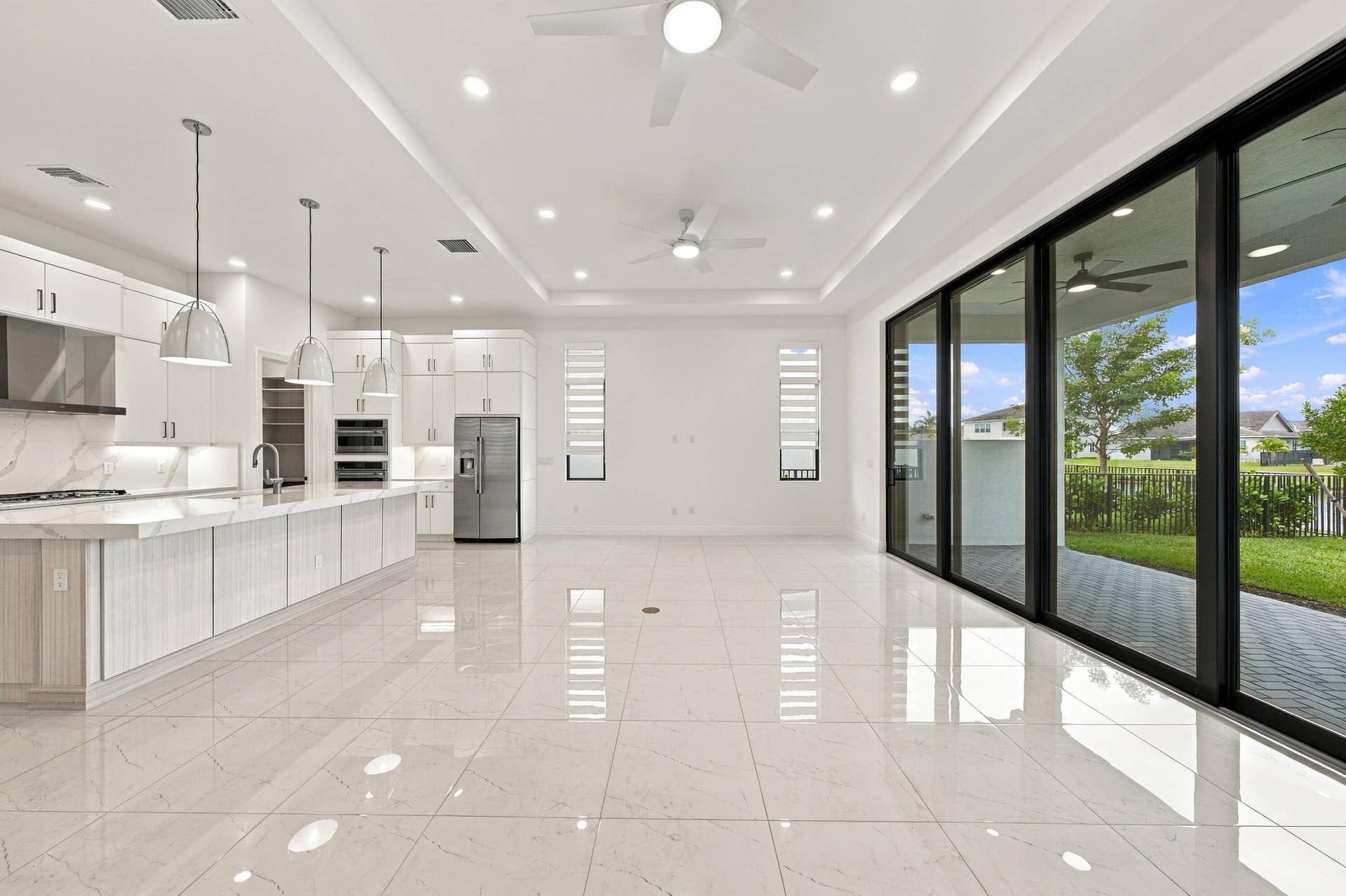 4931 Rivo Alto Circle, Westlake, FL 33470 Great room with tray ceilings and upgraded 10ft high x 16ft long sliding glass doors, ceiling fans, island pendant lights