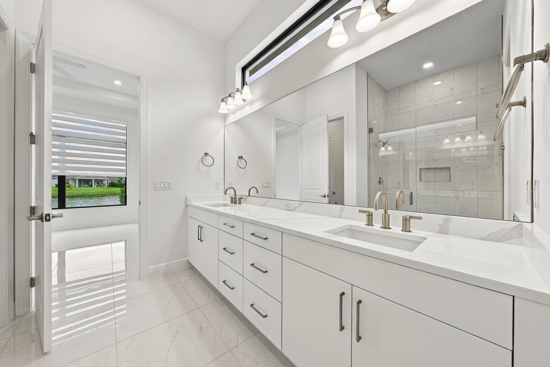 4931 Rivo Alto Circle, Westlake, FL 33470 Primary bathroom with double sinks and vanity lights, upgraded cabinets and quartz countertops, transom window