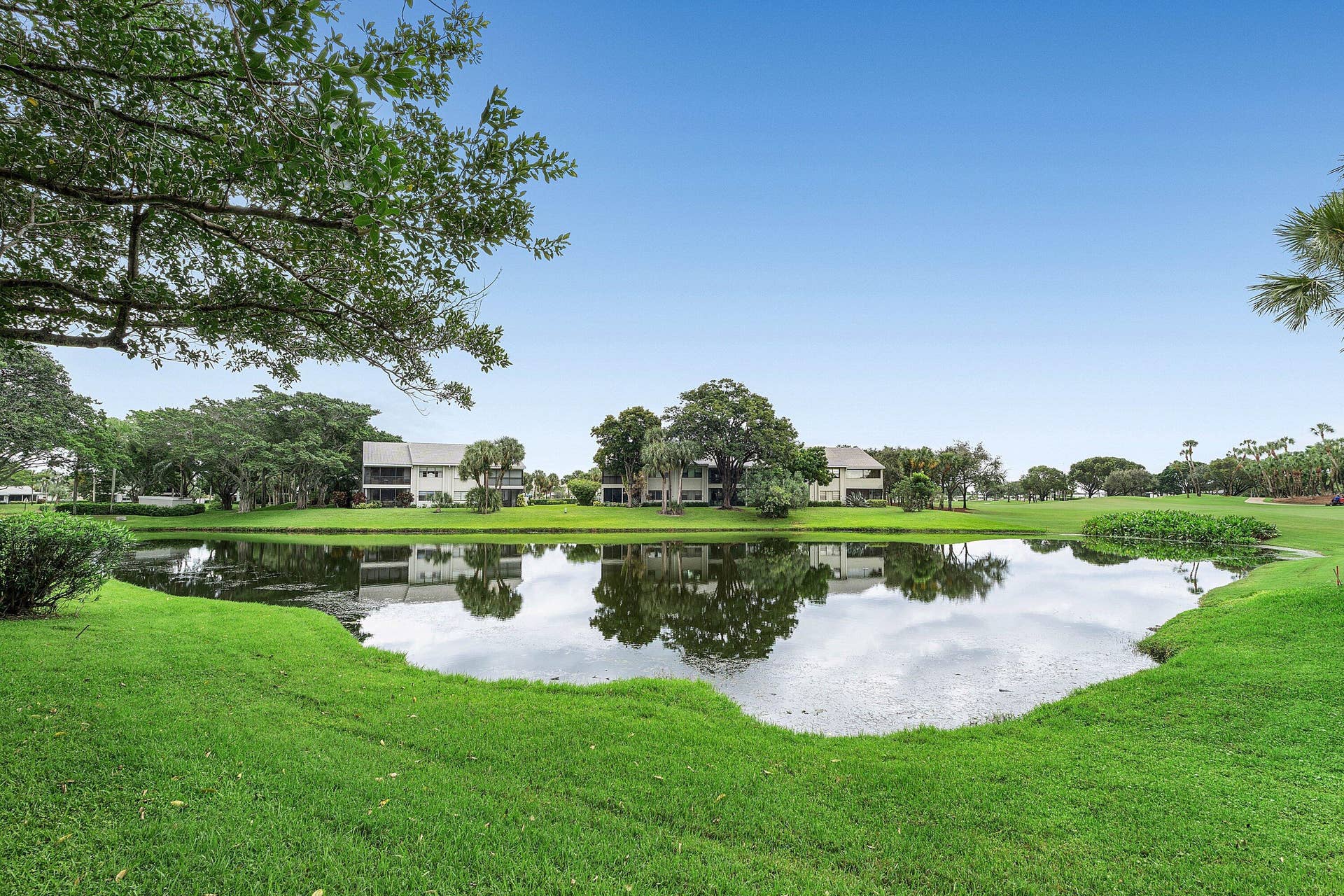 53 EASTGATE Drive, #B, Boynton Beach, FL 33436 Expansive water feature bordered by manicured lawn, mature trees, and landscaping