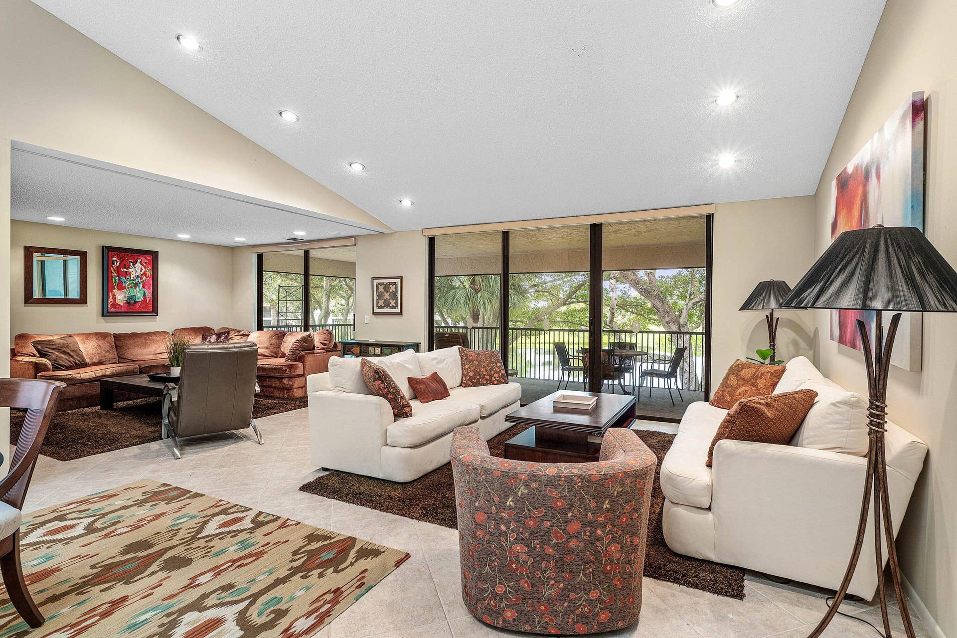 53 EASTGATE Drive, #B, Boynton Beach, FL 33436 Vaulted ceilings with recessed lighting, large-format tile flooring, and floor-to-ceiling glass sliding doors opening to a covered balcony