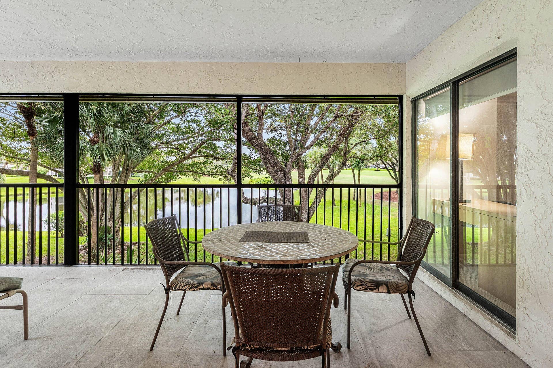 53 EASTGATE Drive, #B, Boynton Beach, FL 33436 Screened-in patio featuring tile flooring, black metal railing, and sliding glass door entry