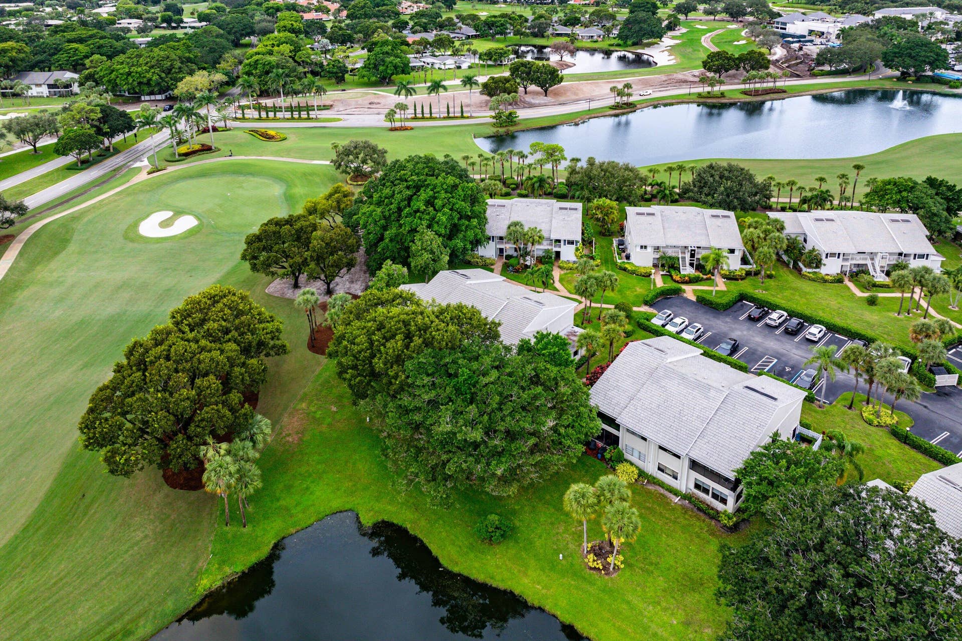 53 EASTGATE Drive, #B, Boynton Beach, FL 33436 Aerial perspective featuring multi-story residential structures, manicured lawn areas, mature tree canopy, and direct water frontage