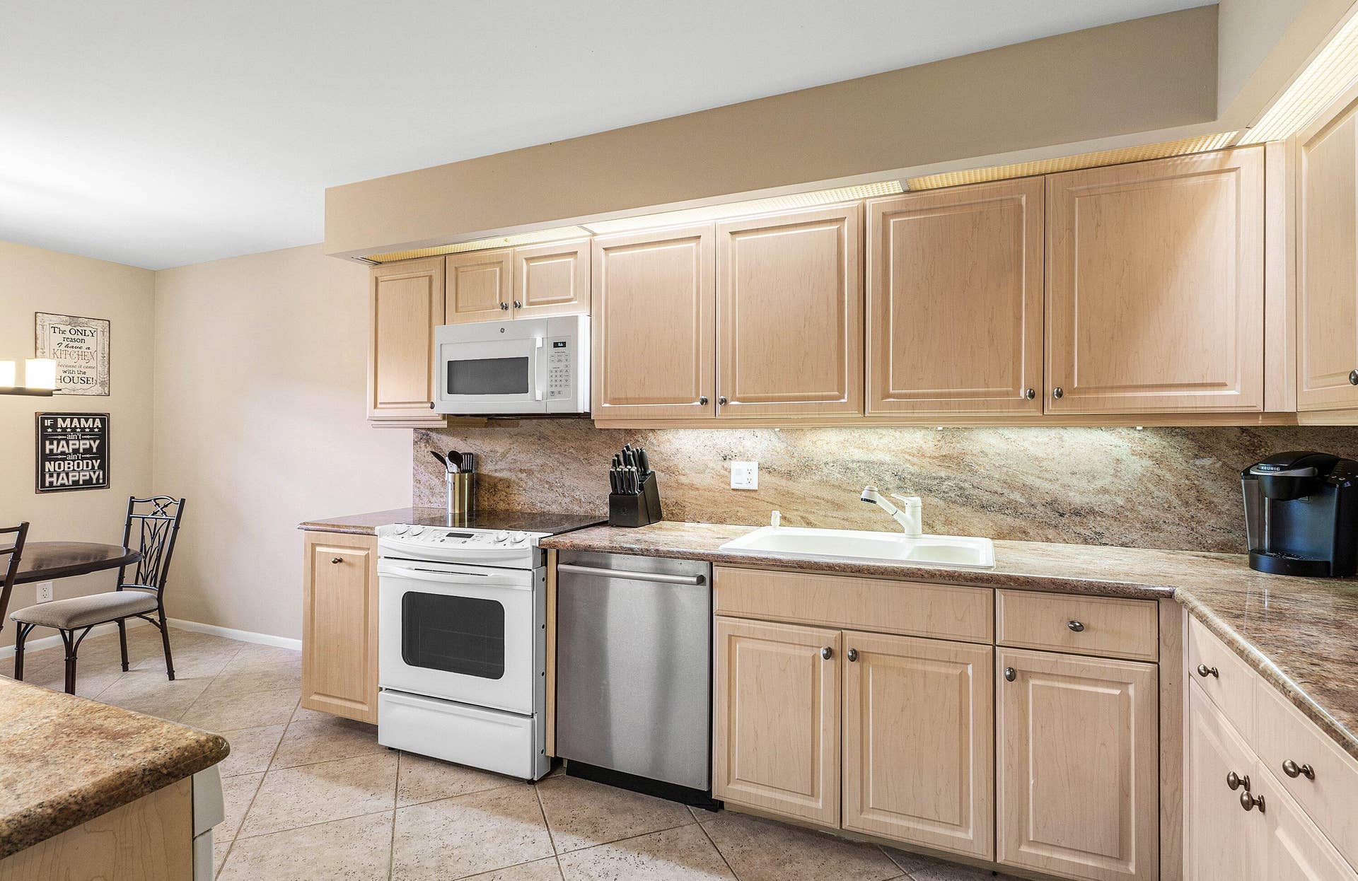 53 EASTGATE Drive, #B, Boynton Beach, FL 33436 Kitchen featuring light wood cabinetry, stone-finish countertops, tile flooring, integrated under-cabinet lighting, and a stainless steel dishwasher