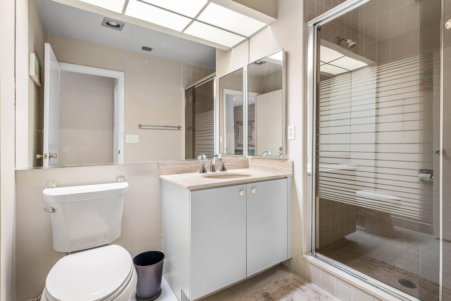 53 EASTGATE Drive, #B, Boynton Beach, FL 33436 Bathroom featuring a single-sink vanity with light-toned countertop, floor-to-ceiling mirror, integrated recessed lighting, and a glass-enclosed shower with horizontal-patterned frosted privacy glass