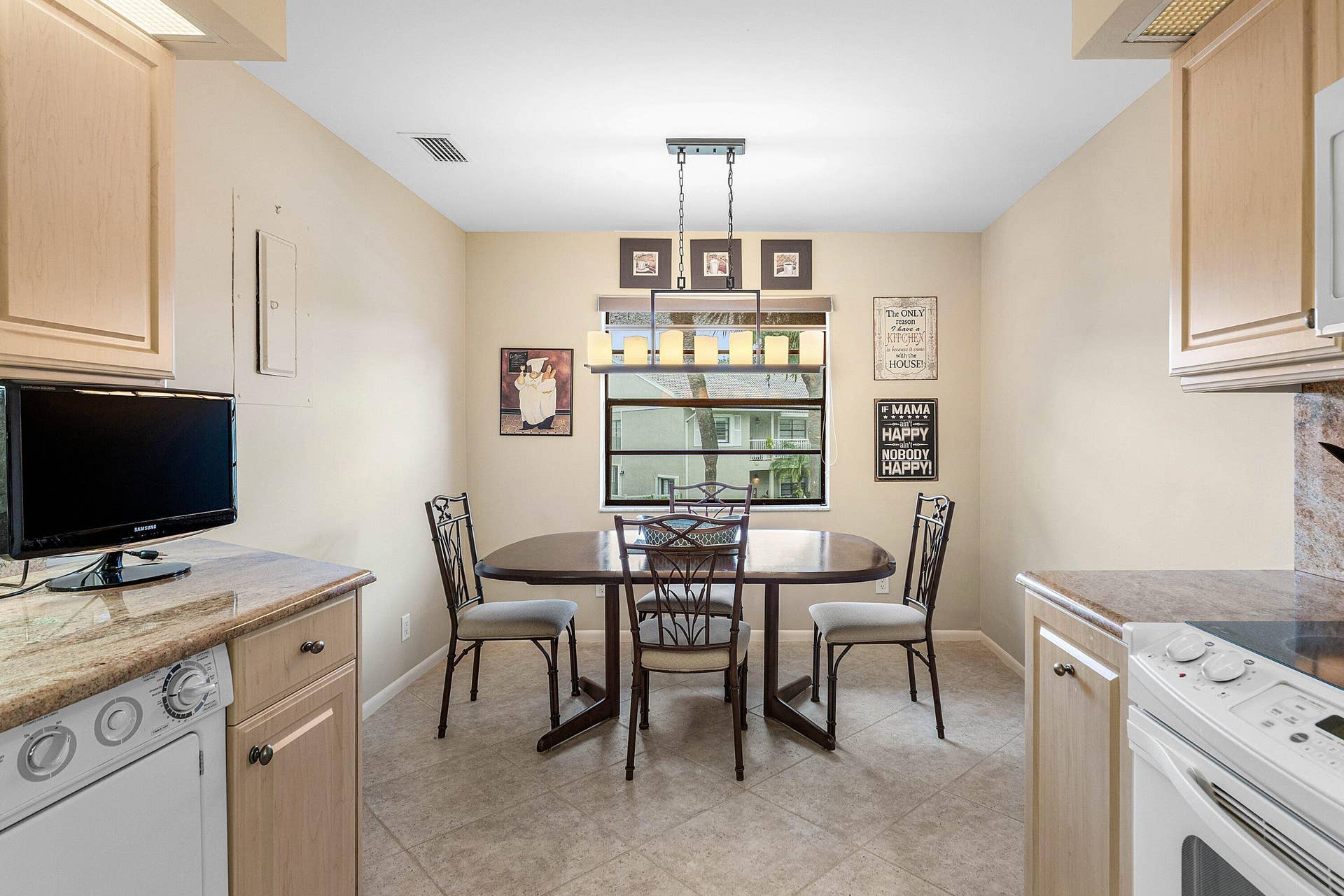 53 EASTGATE Drive, #B, Boynton Beach, FL 33436 Kitchen featuring light wood-finish cabinetry, natural stone countertops, tile flooring, and a linear multi-light pendant fixture