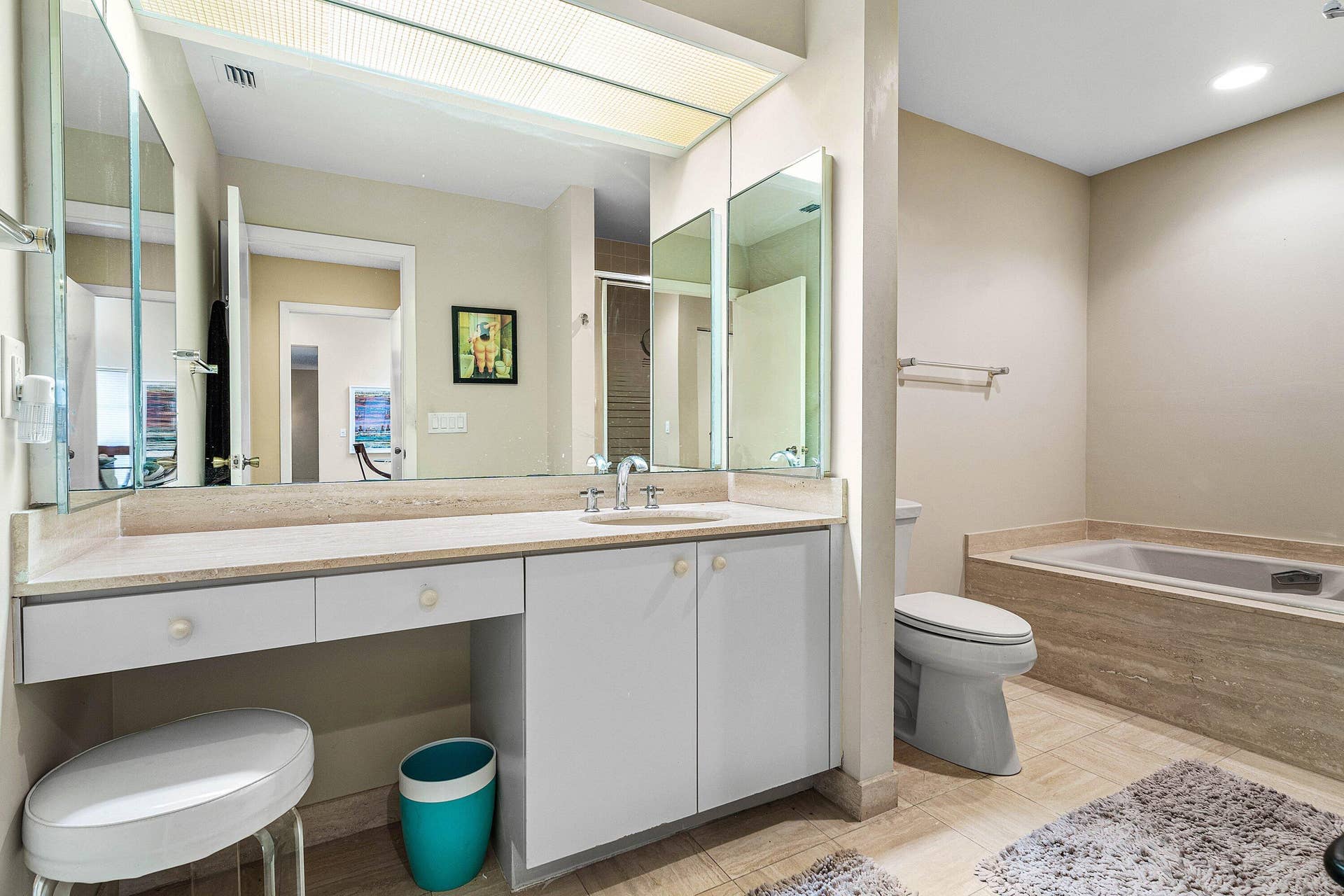 53 EASTGATE Drive, #B, Boynton Beach, FL 33436 Vanity featuring a stone-composite countertop, dual-mirrored wall panels, integrated recessed lighting, and a drop-in sink