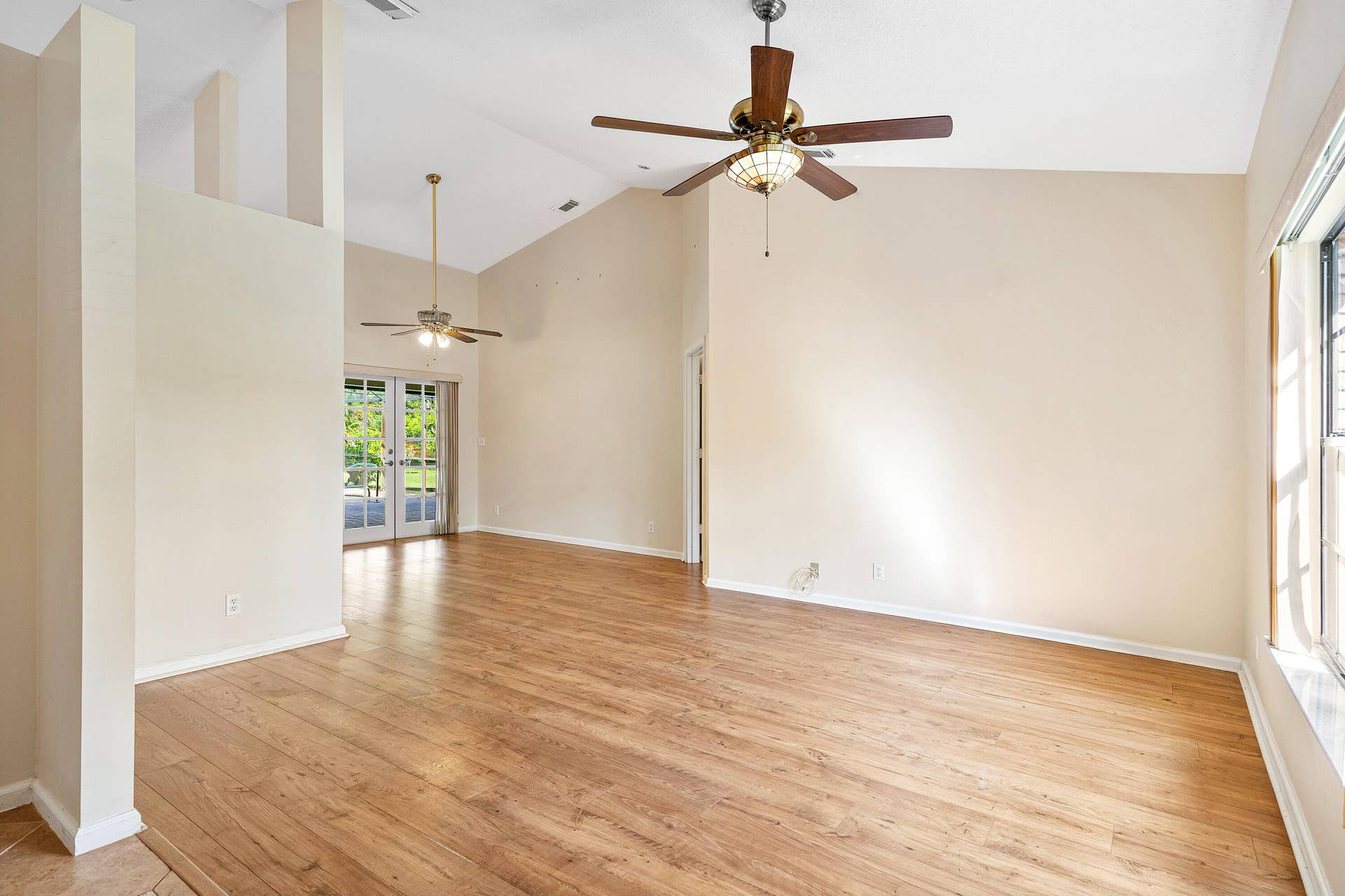 13677 Citrus Grove Boulevard, West Palm Beach, FL 33412 Vaulted ceilings, wood-finish flooring, dual ceiling fans with integrated lighting, and multi-panel French doors