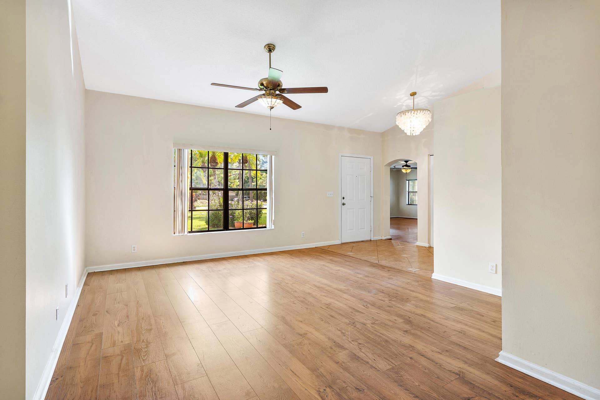 13677 Citrus Grove Boulevard, West Palm Beach, FL 33412 Living area featuring wood-finish flooring, high ceilings, a central ceiling fan with integrated lighting, a multi-pane window, and a decorative chandelier