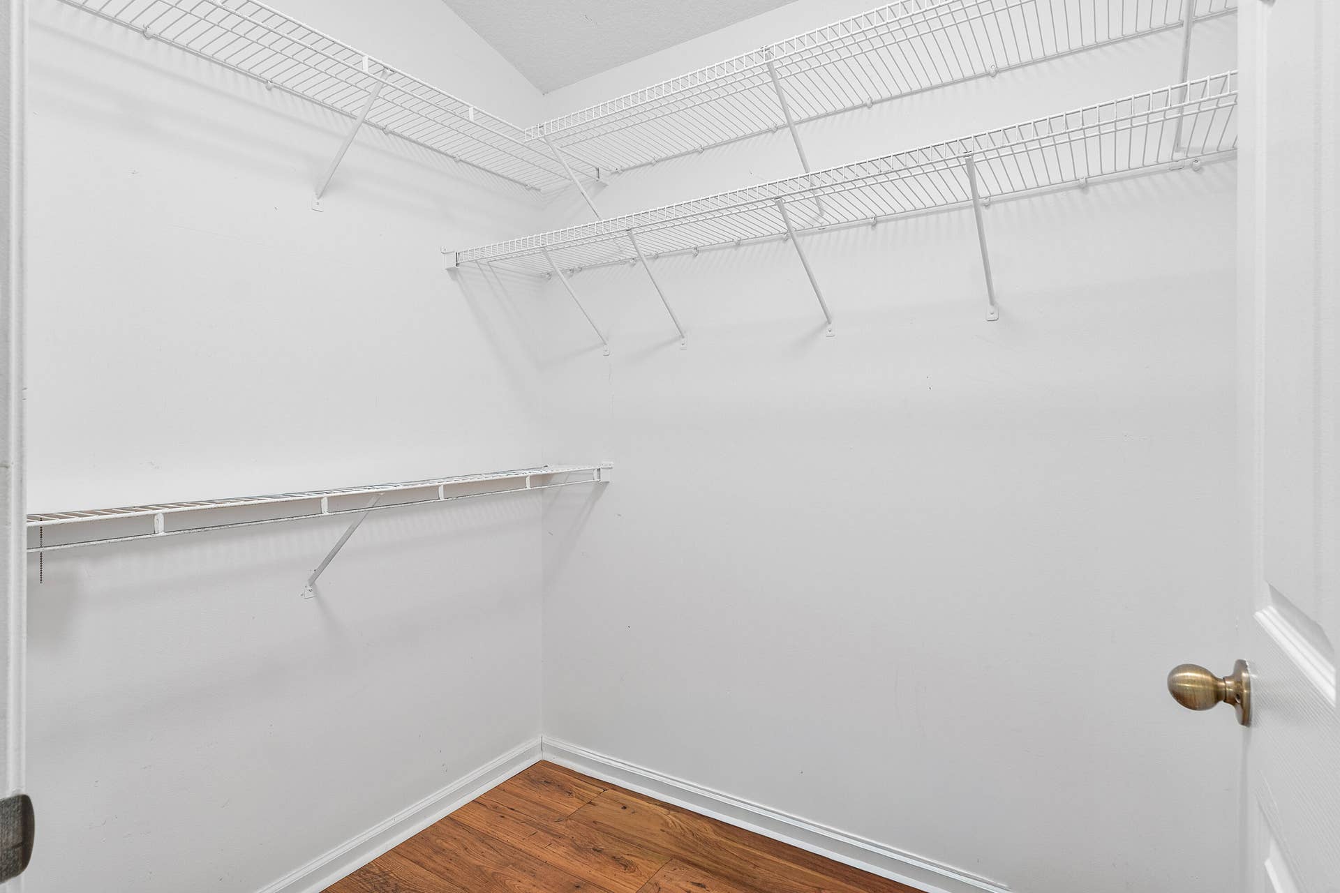13677 Citrus Grove Boulevard, West Palm Beach, FL 33412 Storage area featuring wood-finish flooring and tiered white wire shelving in primary bedroom one.