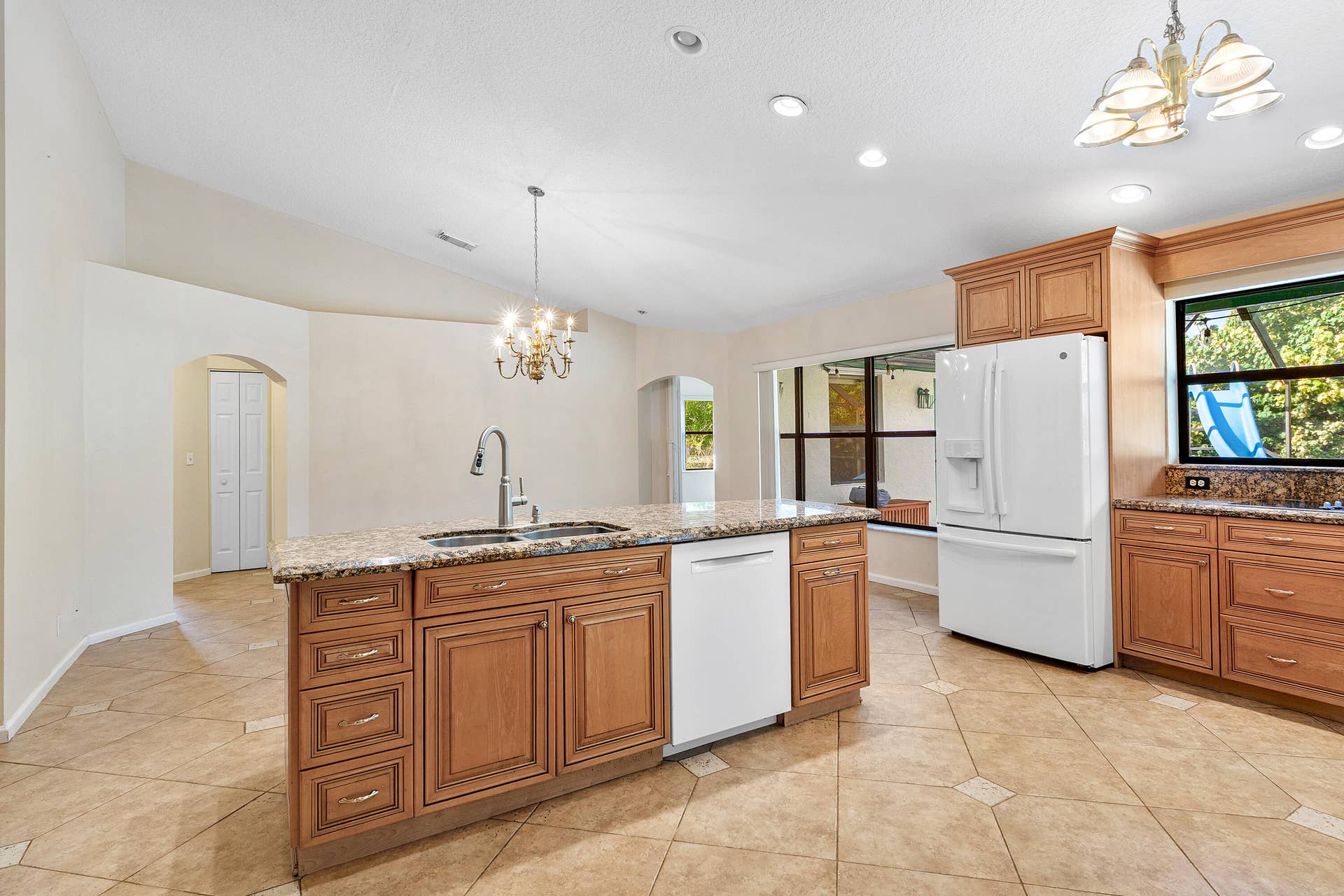 13677 Citrus Grove Boulevard, West Palm Beach, FL 33412 Kitchen featuring wood cabinetry, stone countertops, central island with integrated sink, ceramic tile flooring, and recessed lighting