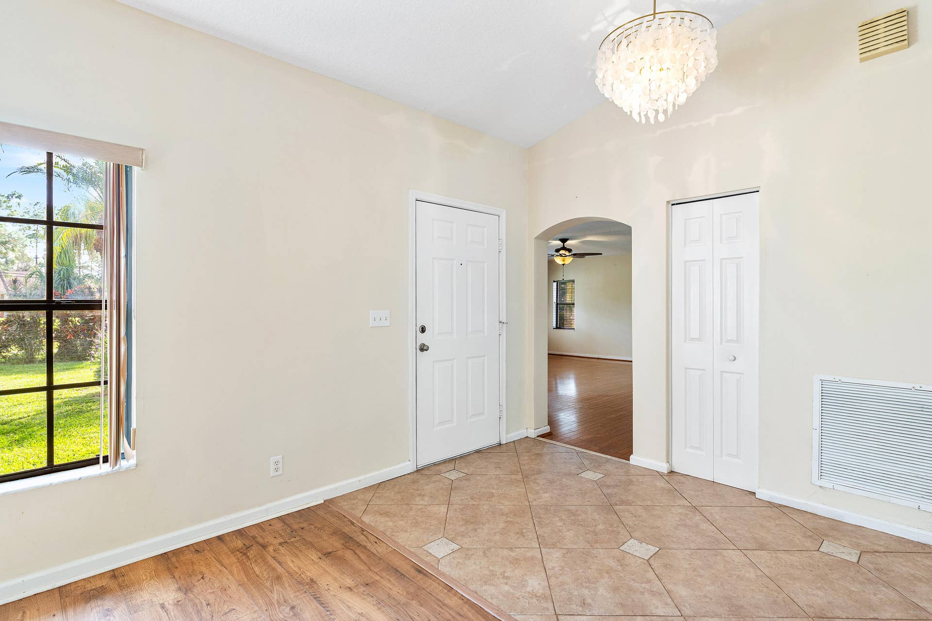 13677 Citrus Grove Boulevard, West Palm Beach, FL 33412 Foyer featuring vaulted ceilings, decorative tiered chandelier, tile flooring with inset accents, multi-pane window, and wood-finish flooring