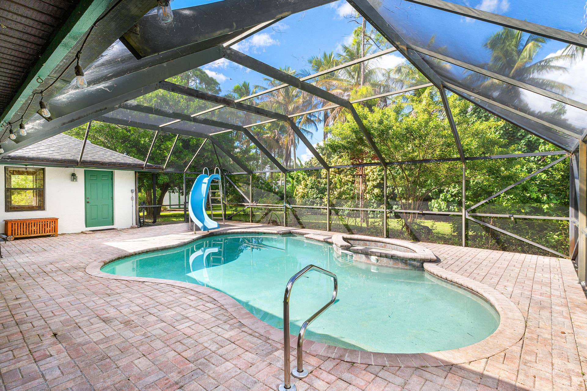 13677 Citrus Grove Boulevard, West Palm Beach, FL 33412 Screen-enclosed patio featuring a paver deck, swimming pool with a built-in slide, and an integrated spa
