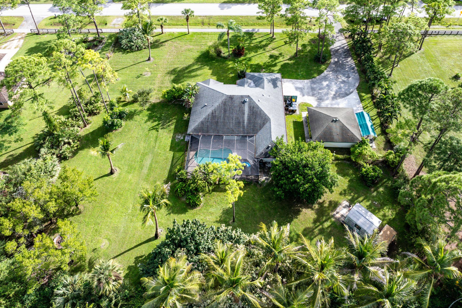 13677 Citrus Grove Boulevard, West Palm Beach, FL 33412 Aerial perspective of a sprawling parcel featuring a multi-structure property, a screened-in swimming pool, a detached garage, and mature landscaping