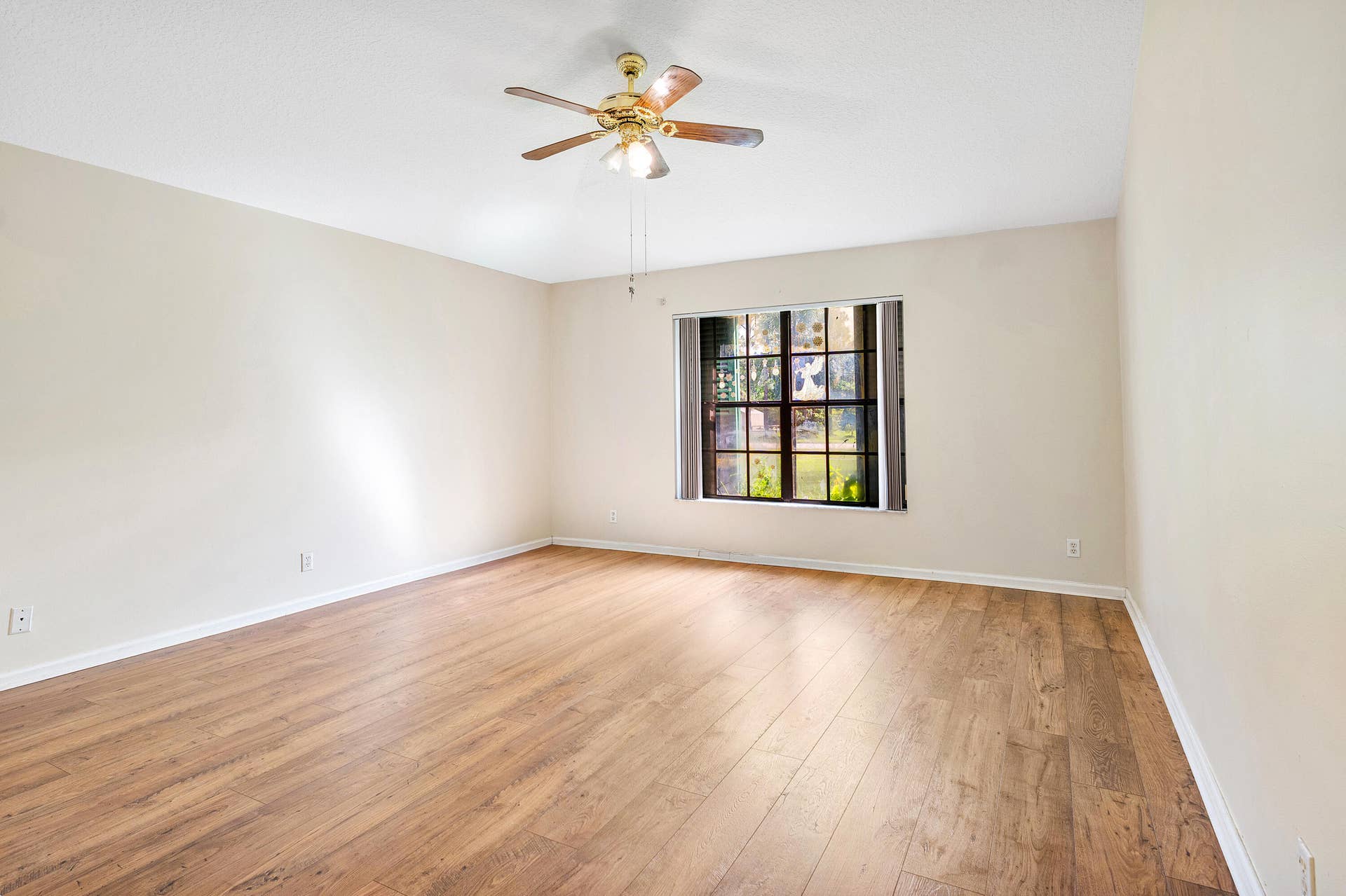 13677 Citrus Grove Boulevard, West Palm Beach, FL 33412 Primary bedroom ensuite number one featuring wood-finish flooring, a multi-pane window, and a ceiling fan with integrated lighting