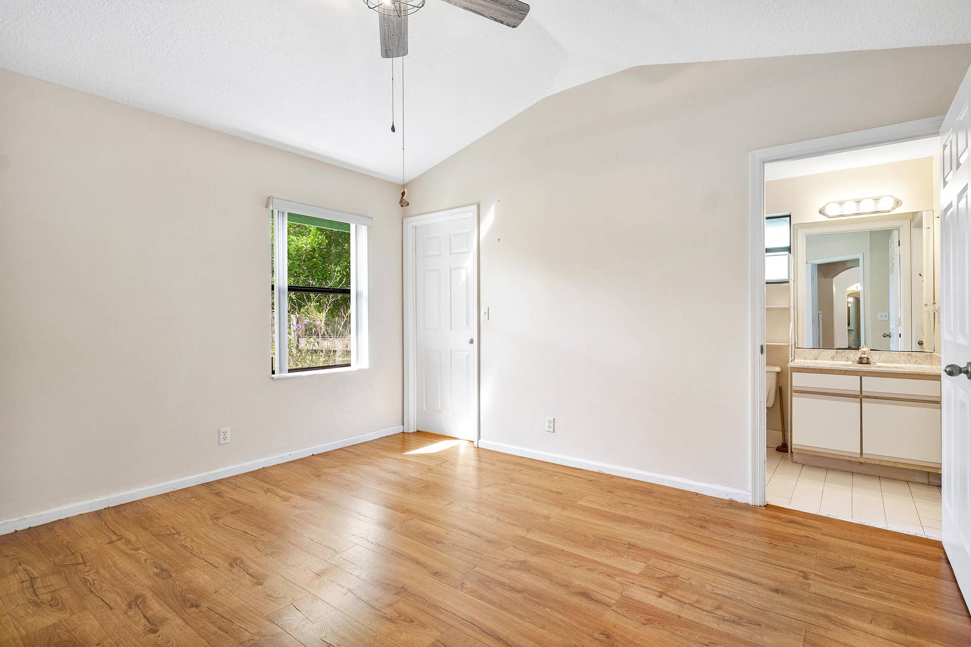 13677 Citrus Grove Boulevard, West Palm Beach, FL 33412 Primary bedroom ensuite number two featuring wood-finish flooring, vaulted ceilings, a ceiling fan, and a single window
