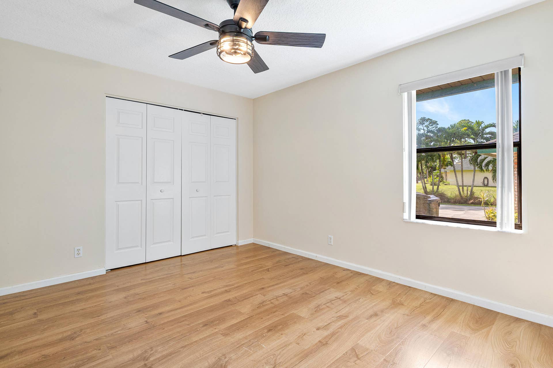 13677 Citrus Grove Boulevard, West Palm Beach, FL 33412 Bedroom three featuring wood-finish flooring, a multi-panel closet with white doors, and a ceiling fan with integrated lighting