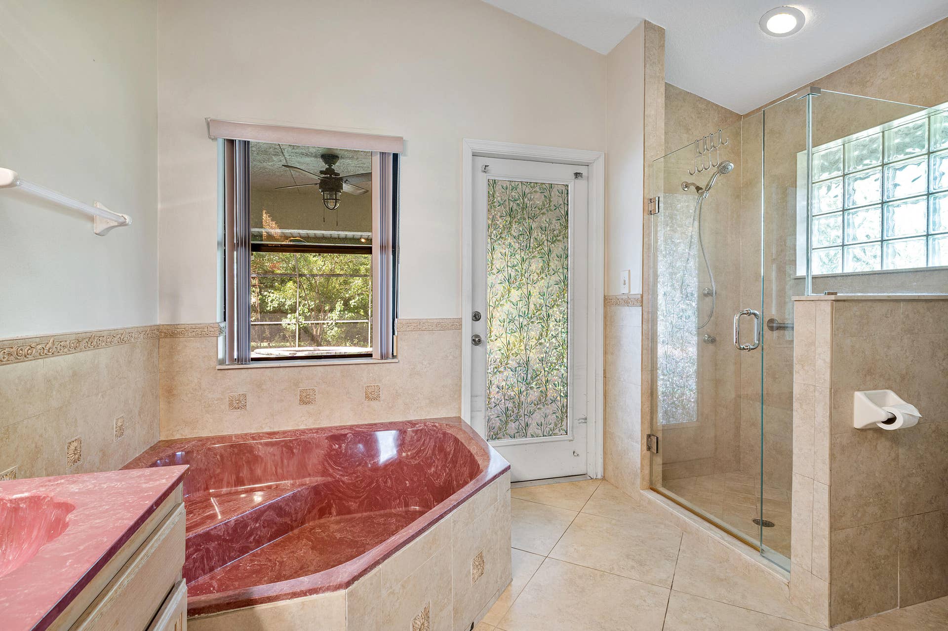 13677 Citrus Grove Boulevard, West Palm Beach, FL 33412 Primary bathroom ensuite number one featuring a custom built-in soaking tub, a glass-enclosed shower with tile surround, a frosted glass exterior door, ceramic tile flooring, and a glass block window